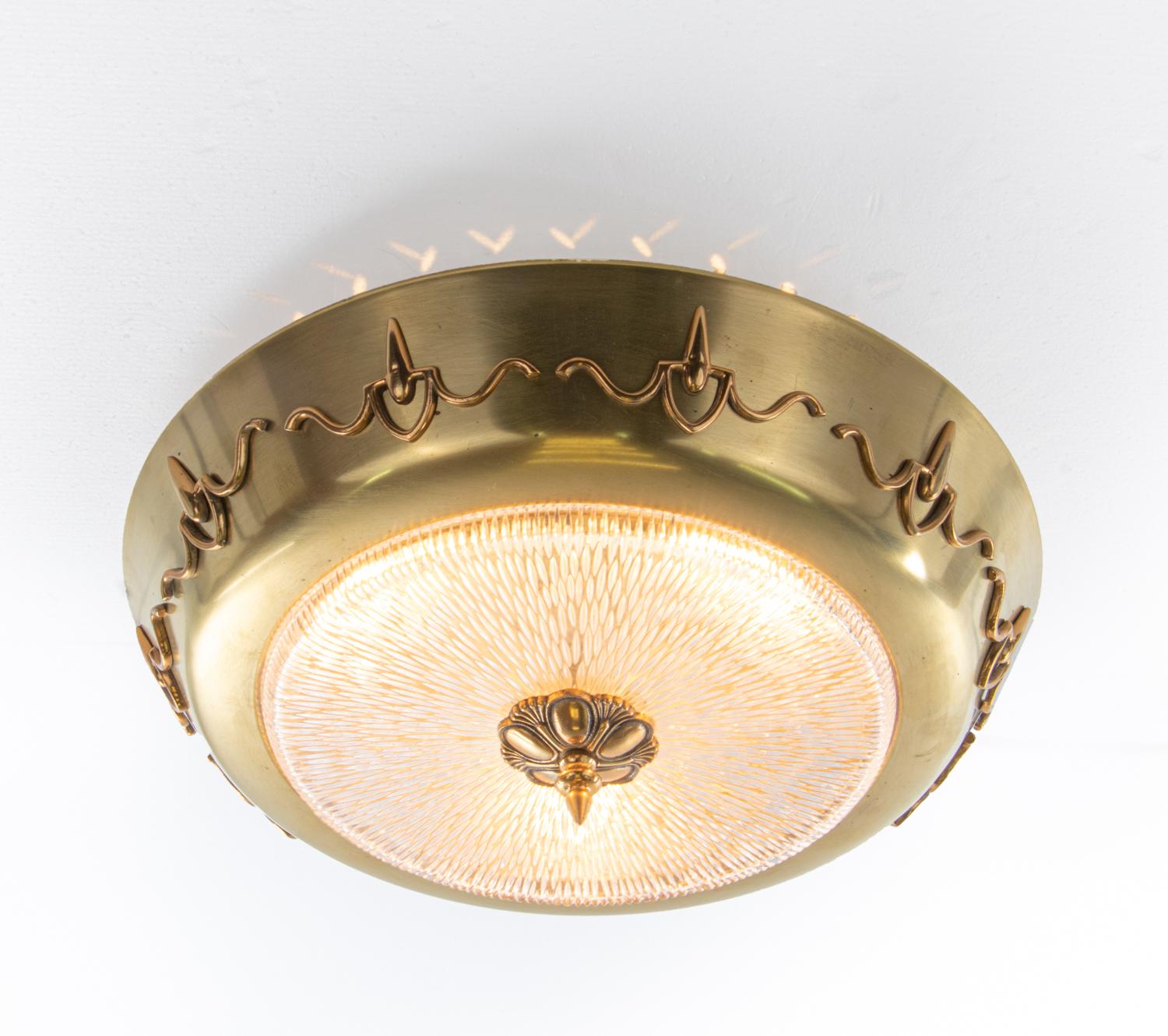 European Art Deco brass and textured glass flush light. 

Manufacturer: unknown. 
Execution: round. 
Style: art deco, mid century, modernist. 
Materials: glass and brass. 
Colors: clear and golden. 
Measures: width appr. 17.3