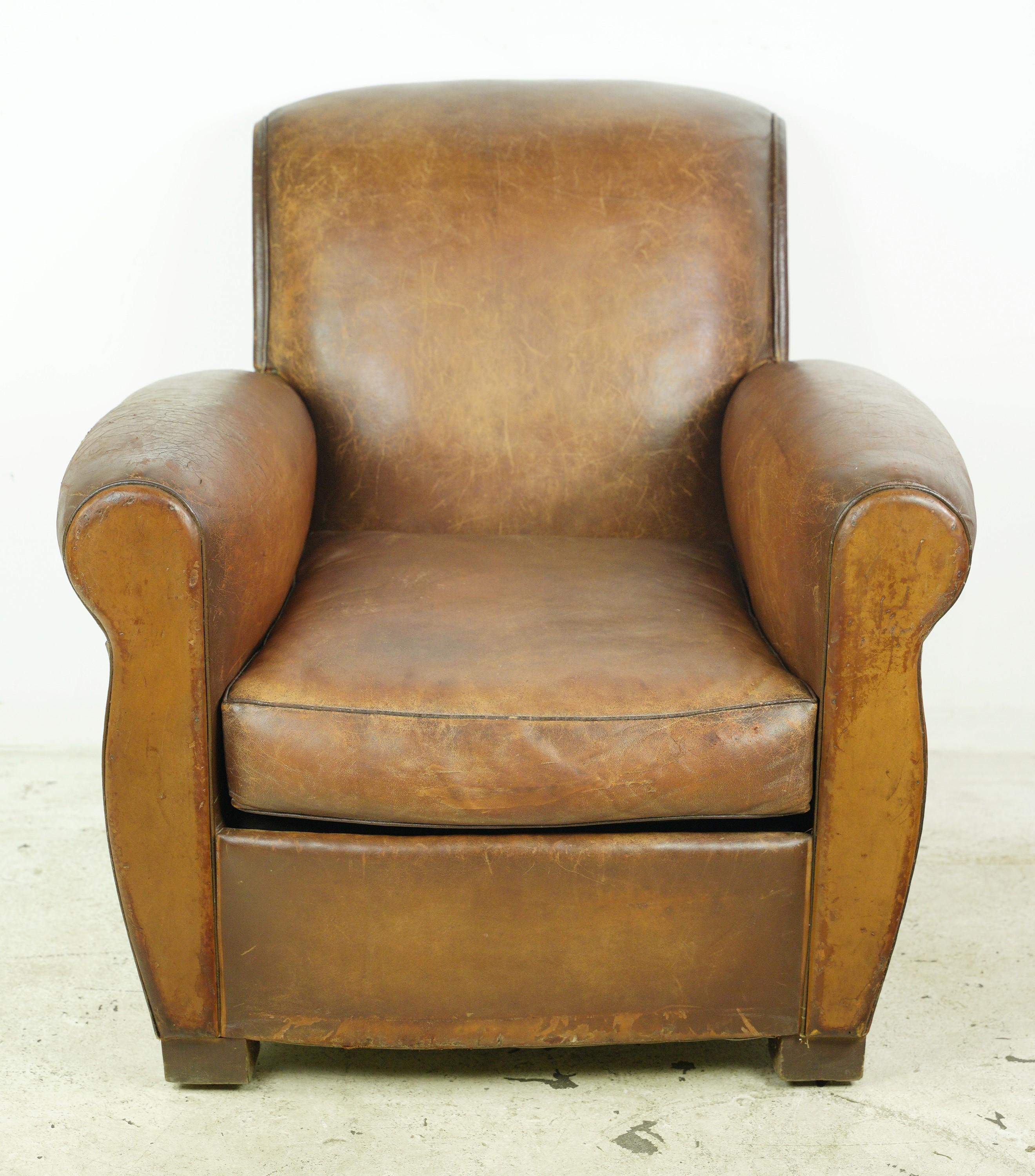 This European club chair upholstered in brown leather is adorned with steel studs, featuring wood feet. This chair combines the comfort of leather with the classic appeal of steel studs and wood details, creating a stylish and inviting seating