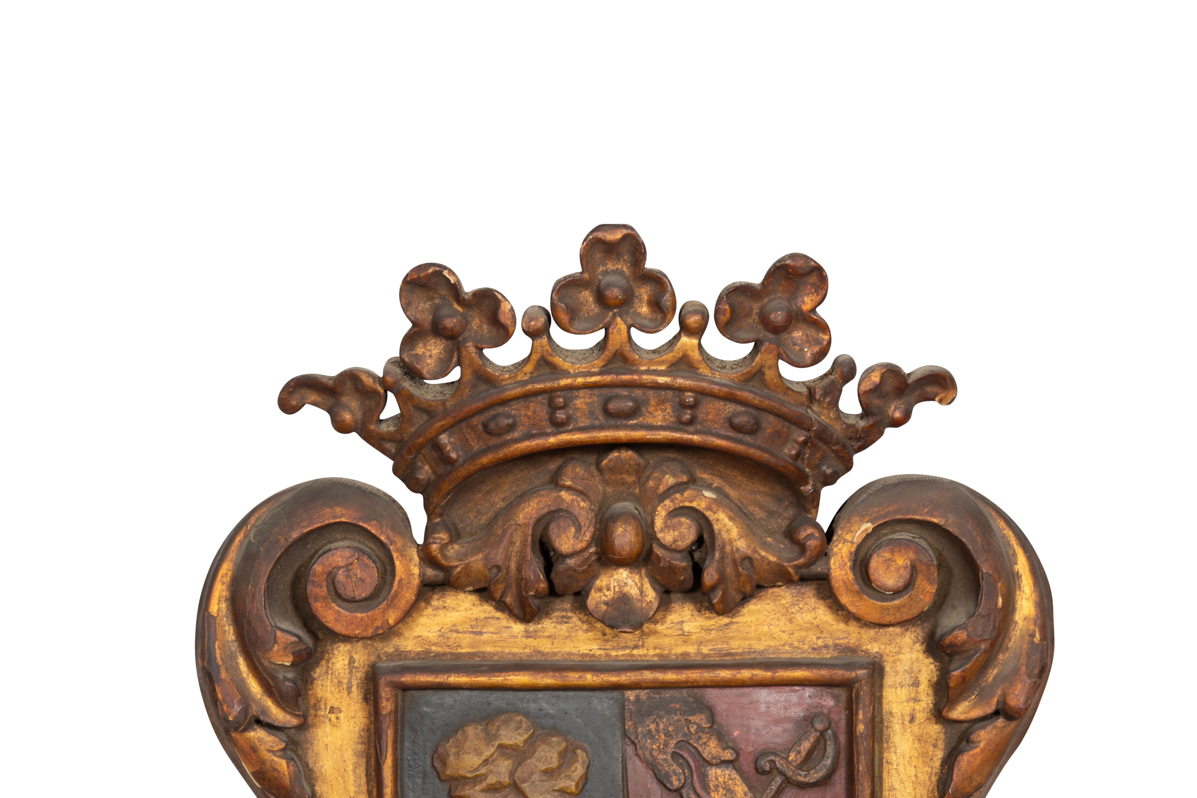 Shield form with a crown over a coat of arms with different symbols, the frame carved and gilded in the baroque style. From the Michael Kittredge collection.