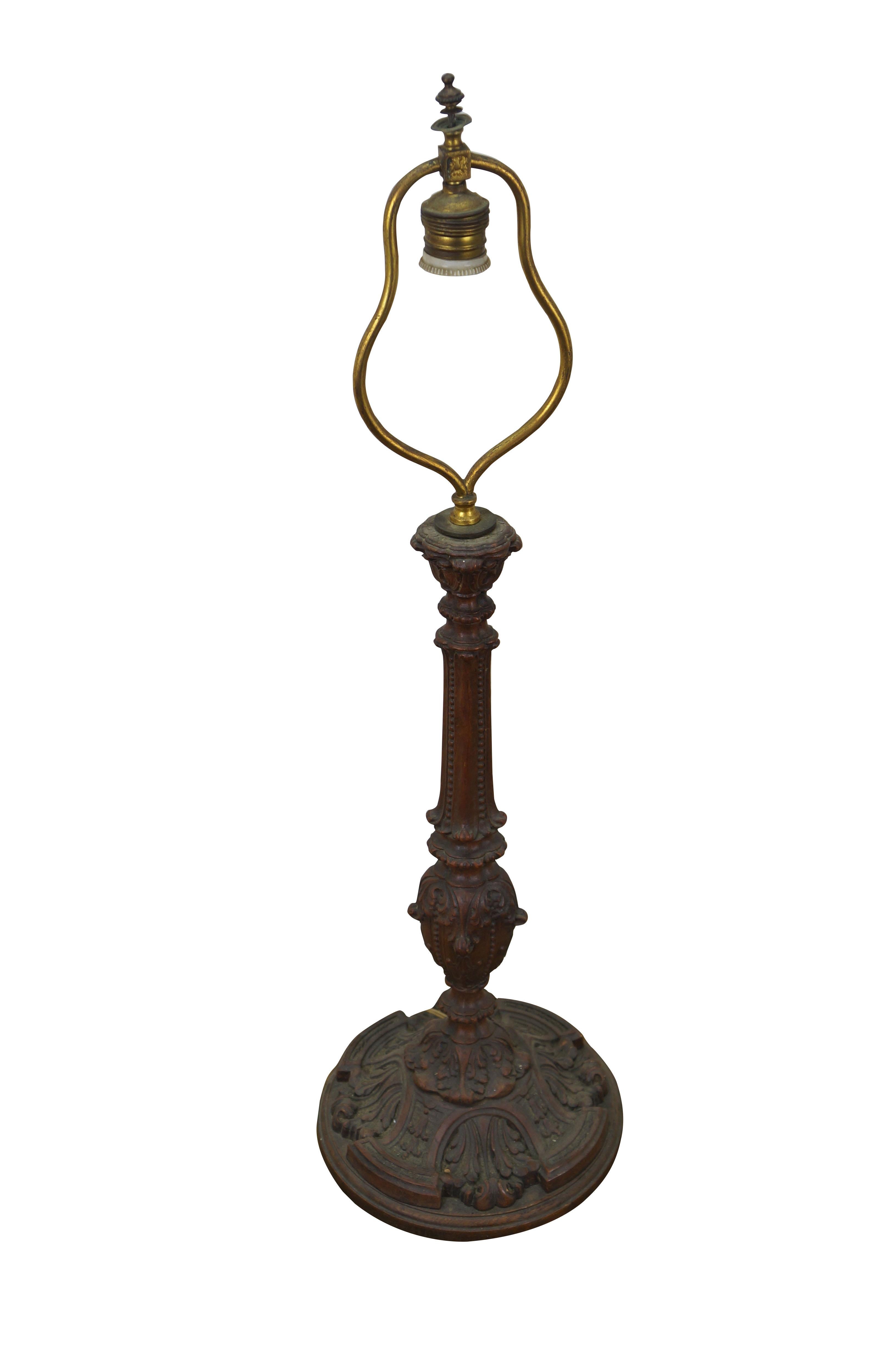 Vintage oak wood table lamp featuring ornately carved designs with a round base and baluster shaped candlestick column, accented with scallops, beading and acanthus leaves. Attached gilt brass harp. Includes finial.

Dimensions:
8.75