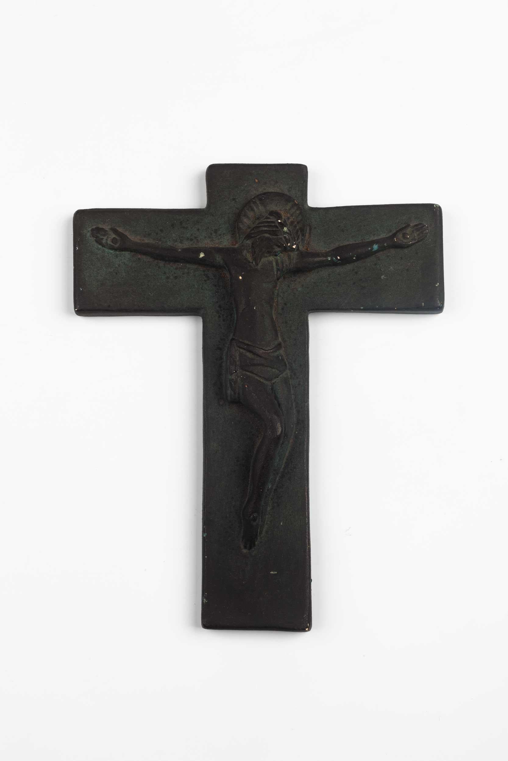 Belgian wall cross in matte black, hand painted ceramic with halo-ish Christ figure in volume.

From modernism to brutalism, the crosses in our collection range from being as futurist as a modernist church to as raw as a brutalist building. Each