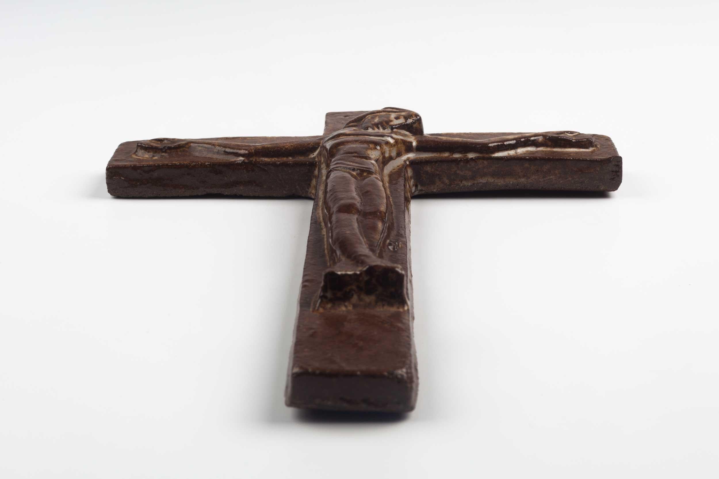 Belgian wall cross in ceramic, hand painted in semi-gloss earthy brown with abstract Christ figure in volume.

From modernism to brutalism, the crosses in our collection range from being as Futurist as a modernist church to as raw as a Brutalist