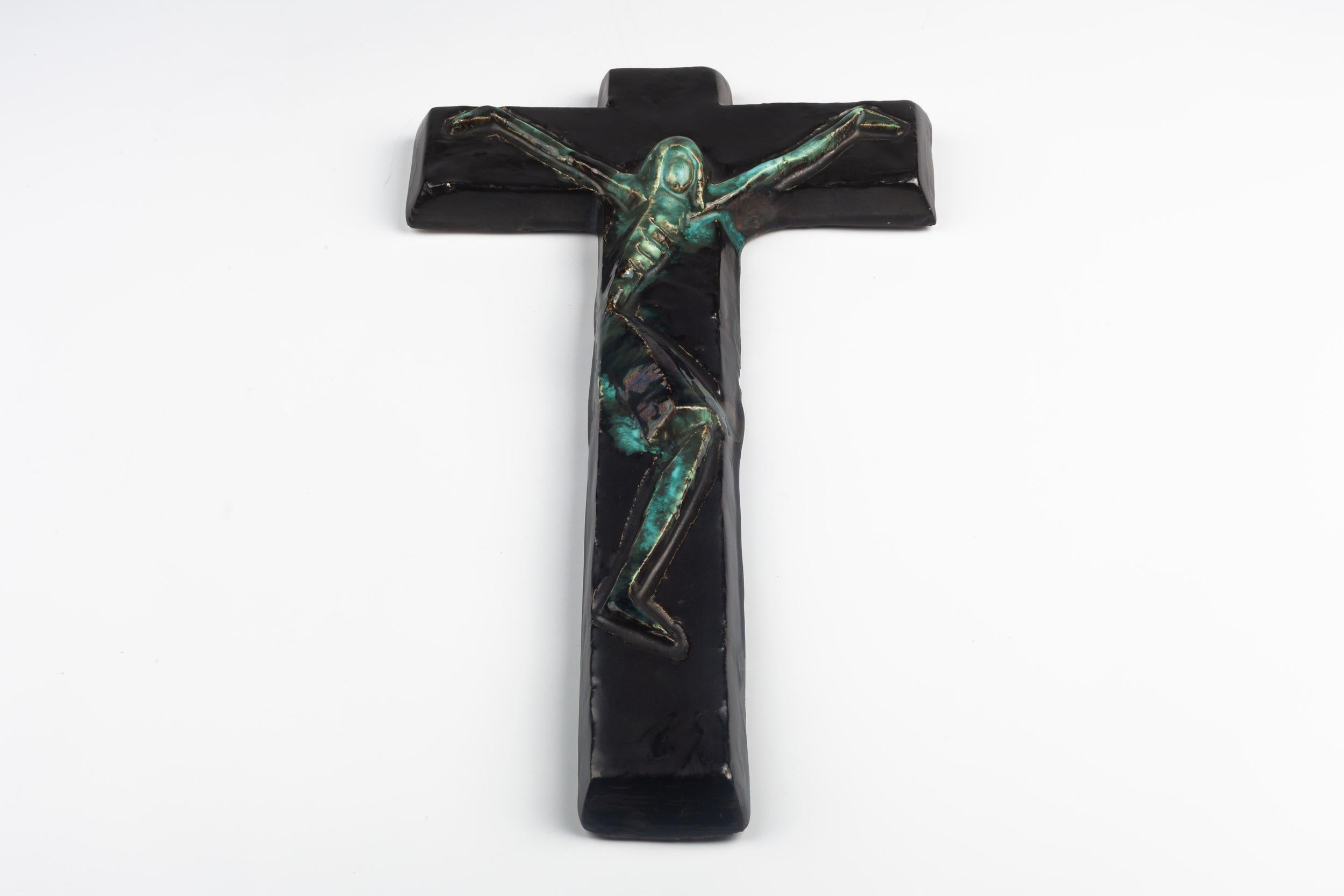Belgian wall cross in ceramic, hand painted in glossy black with blues and greens on an abstracted Christ figure.

From modernism to brutalism, the crosses in our collection range from being as futurist as a modernist church to as raw as a