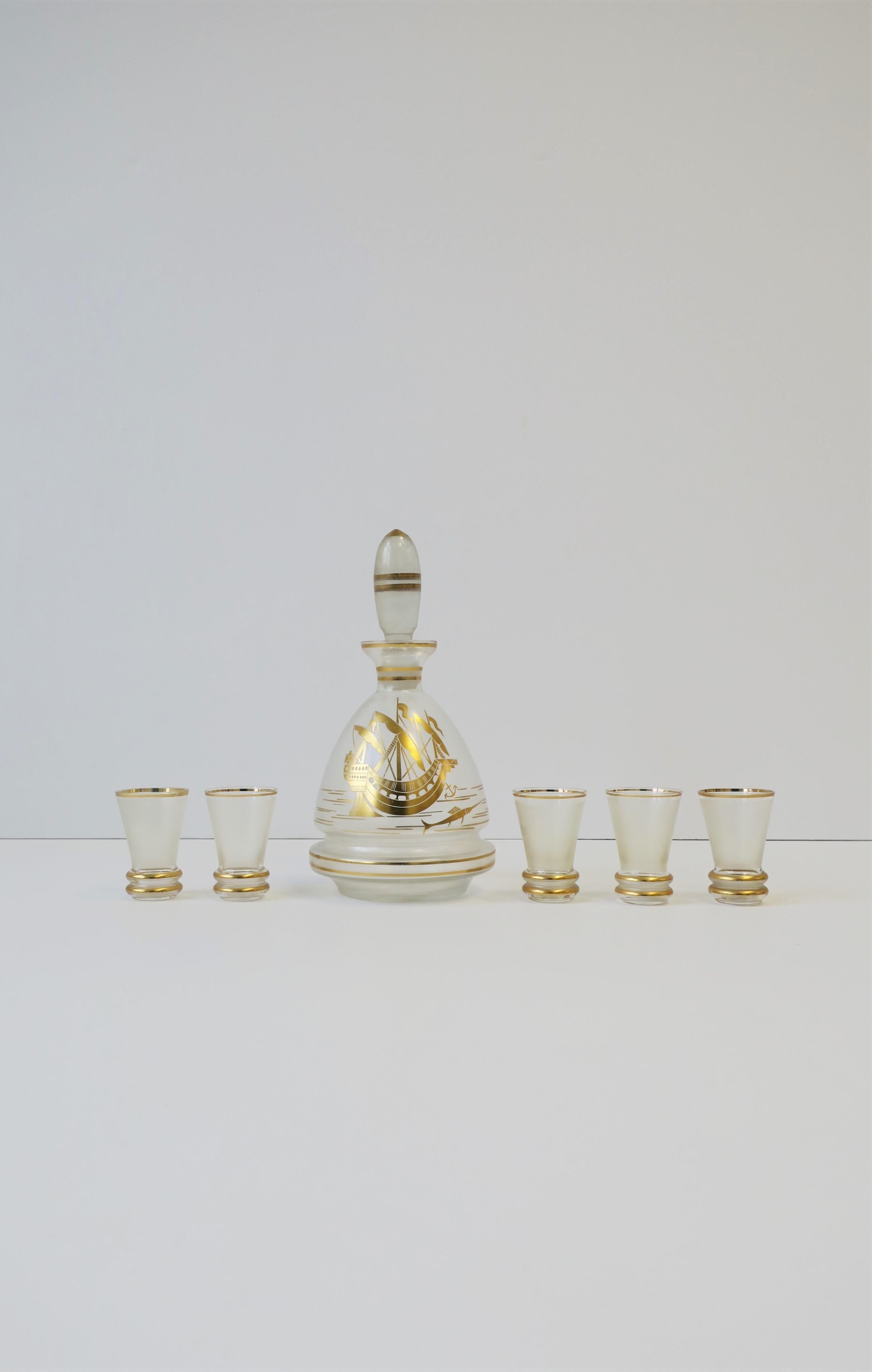 A very beautiful clear and gold spirits or liquor decanter and shot glass set from Czechoslovakia, circa mid-20th century, Europe. Beautiful gold details include nautical scene of a ship with sails, boat anchor, and swordfish. Each shot glass is