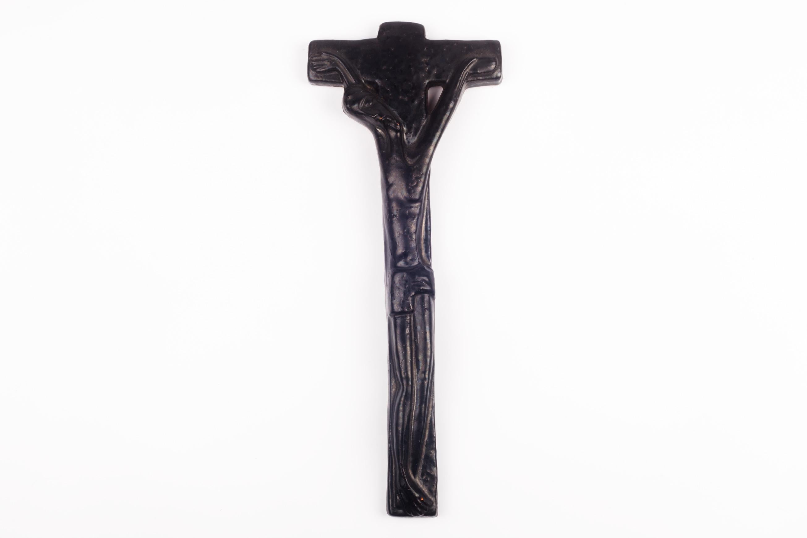 European crucifix in black glazed ceramic. Modernist and brutalist Christ figure with charismatic lines and overly bent neck. The visionary all-black piece is highlighted solely by dark reflections. A one-of-a-kind, handcrafted piece that is part of