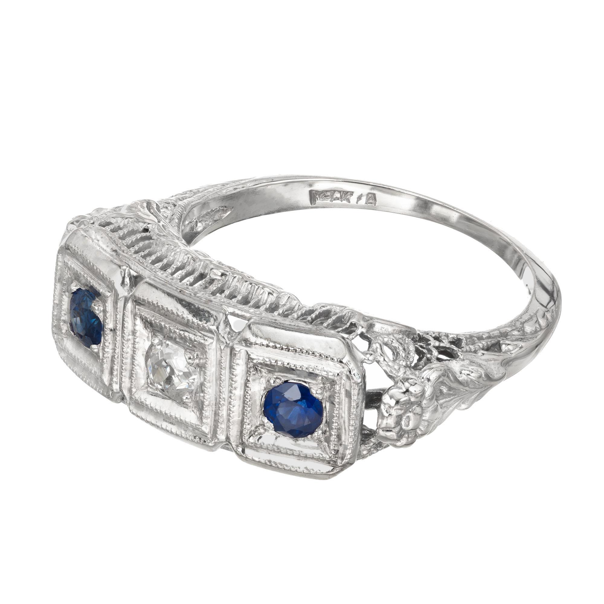 Diamond and sapphire three-stone ring. Filigree sides and shoulders, 14k white gold setting with a flat top set with two Sapphires and one old European cut diamond center. Late Art Deco circa 1940's

1 European cut diamond, approx. total weight