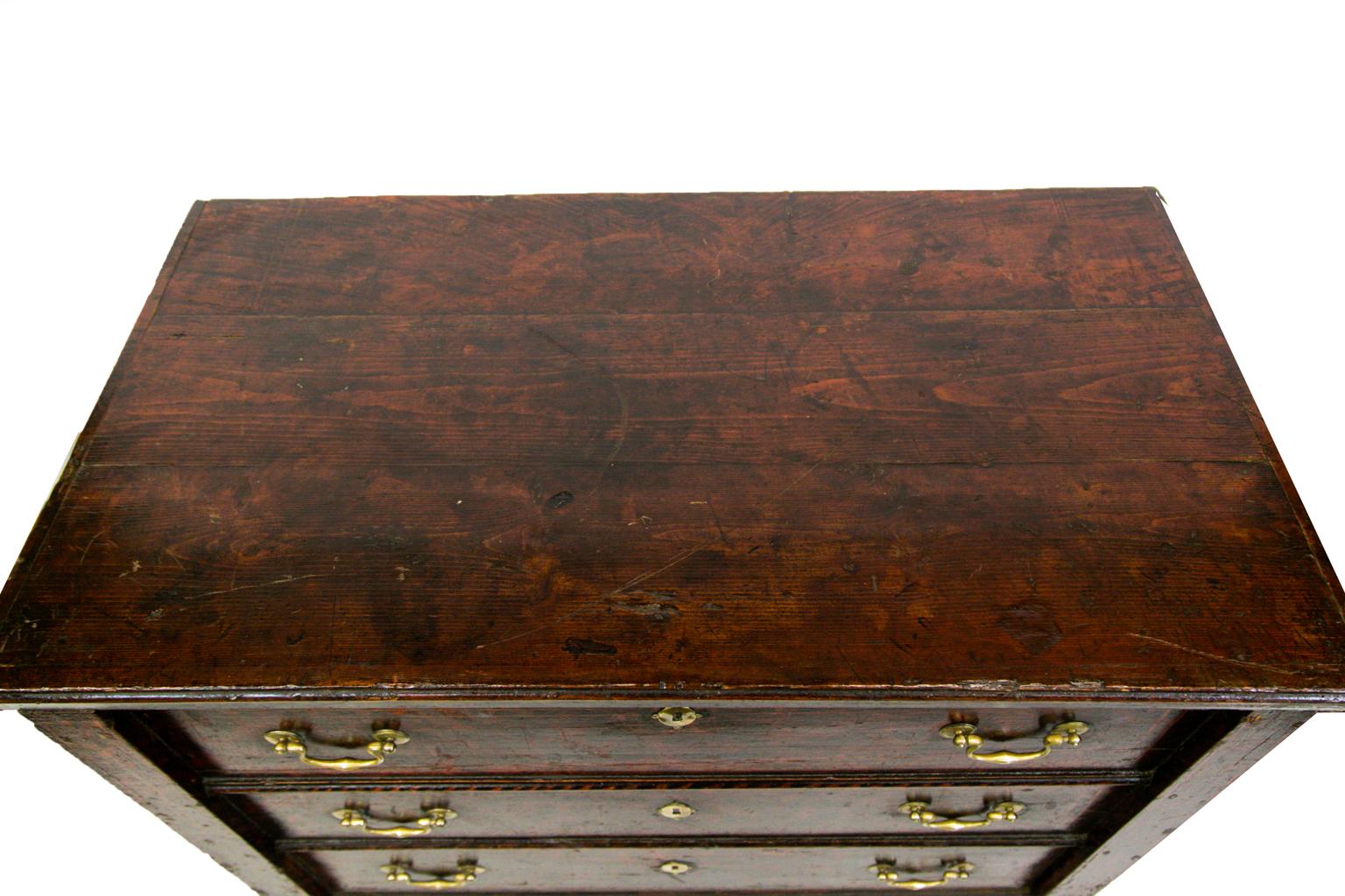European faux painted pine lift top chest on legs. The drawer fronts, stiles, and sides are faux painted to simulate burled wood. The top two drawers are dummies but the bottom is a working one.