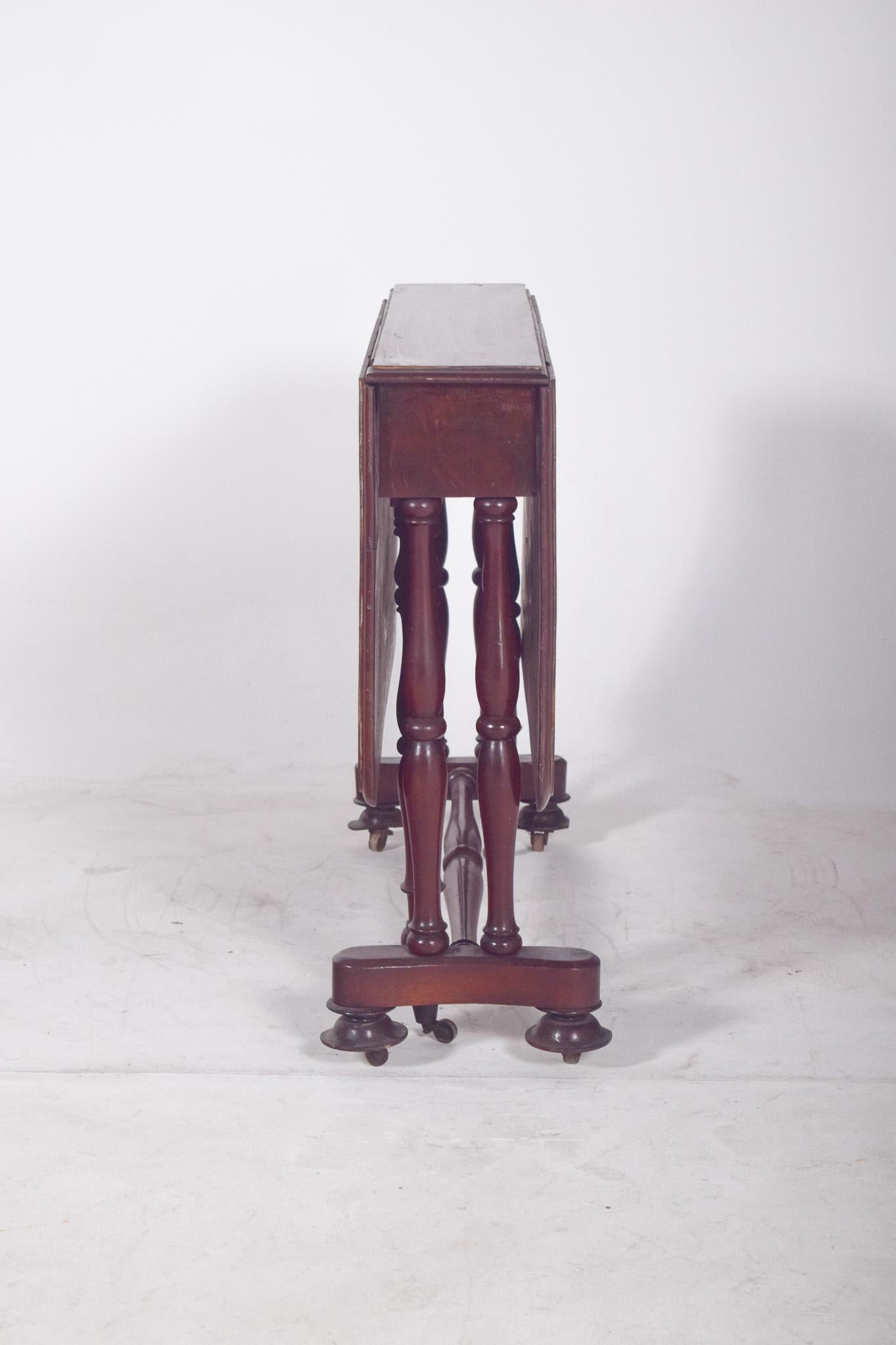 Flap table with turned legs. With a rectangular top and folding sides, it has smooth edges and a flat finish, supported by an elegant set of turned legs, joined by horizontal braces that contribute to the stability of the piece. The structure is