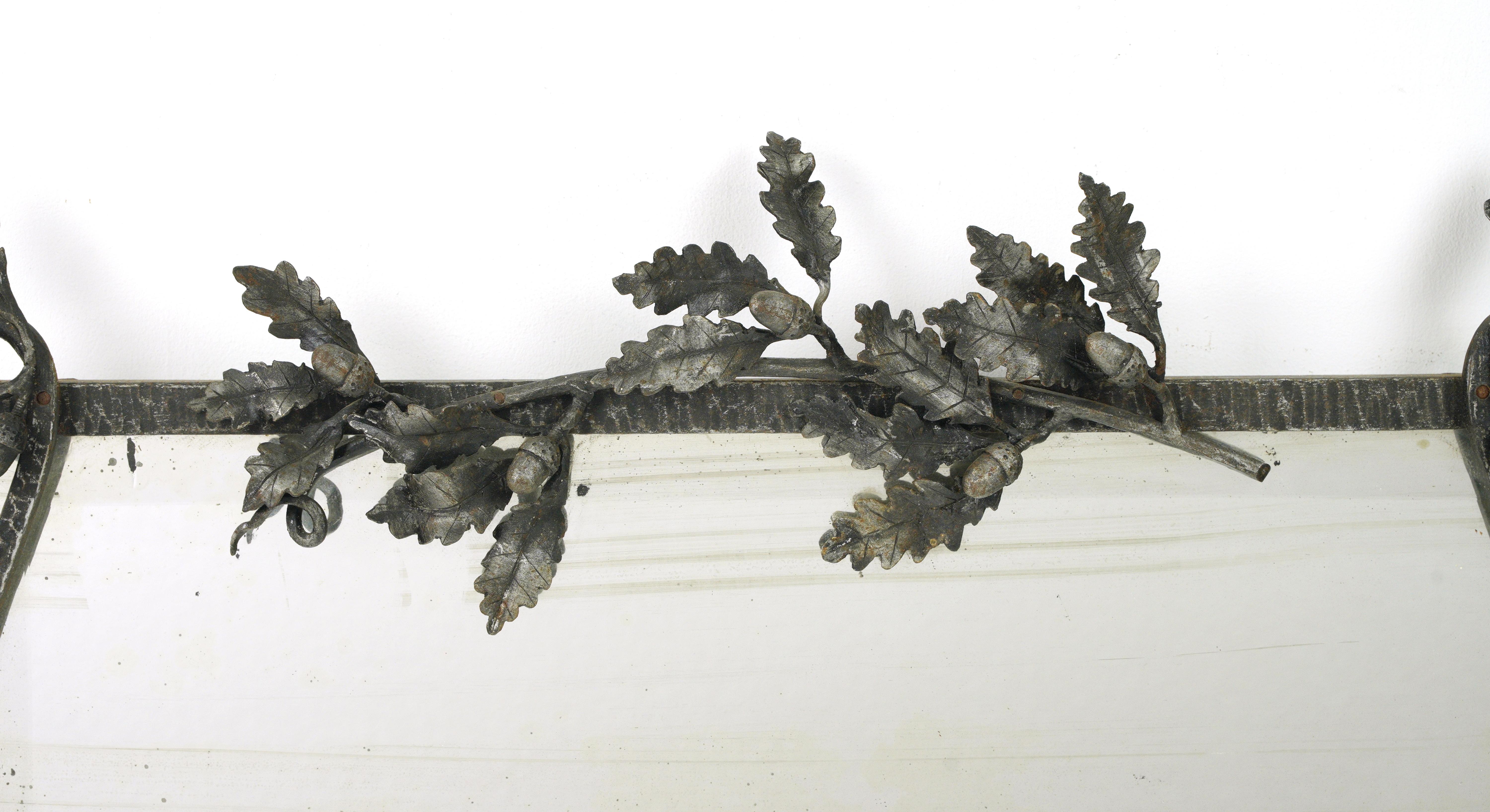 Miroir Art déco français avec un cadre en fer forgé à la main décoré d'une branche en métal de feuilles et de glands. Le miroir présente des dégradations et des stries dues à l'âge. Un disponible. Veuillez noter que cet article se trouve dans nos