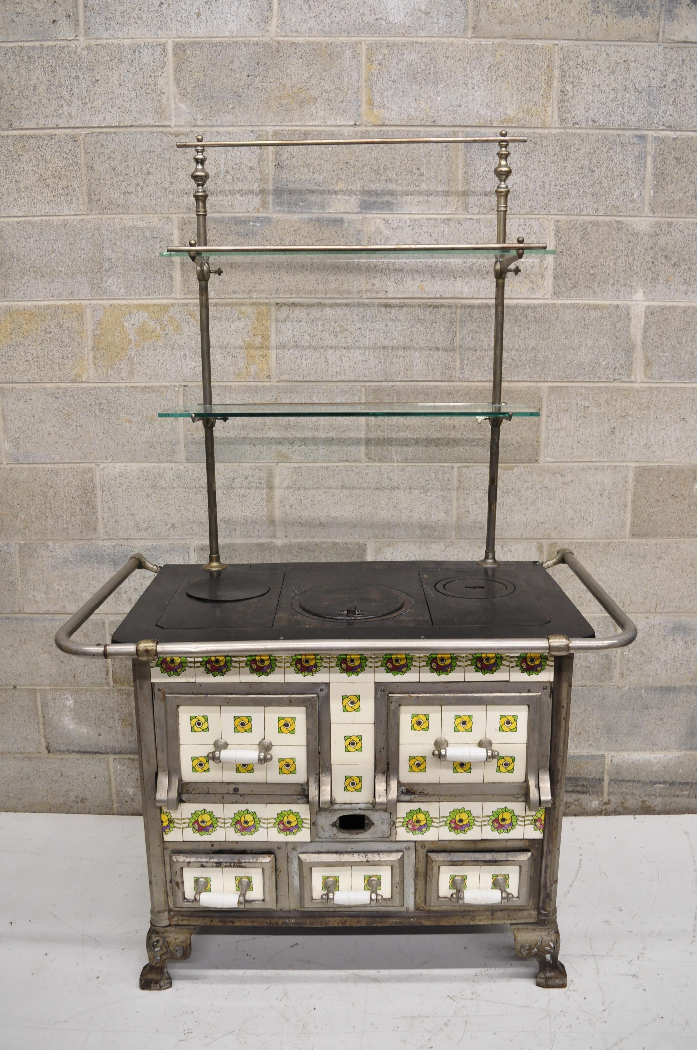 European (Probably Belgium or France) cast iron Art Nouveau glazed tile wood/coal burning stove with bakers rack shelf. Item features glazed stylized floral tiles, the rectangular frame with cast iron top concealing the interior to be filled with