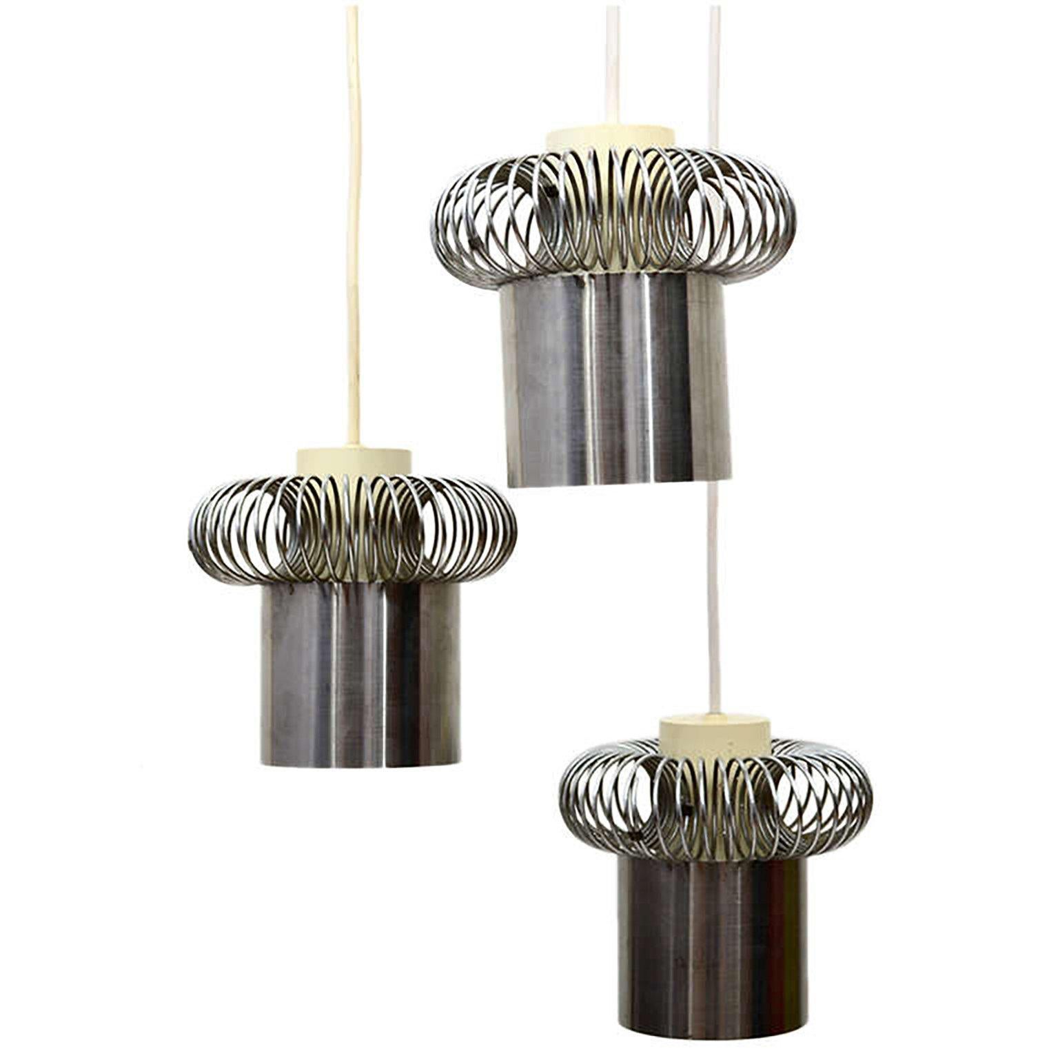 European chandelier constructed with three hanging shades.
Based in the construction, it appears to be a late 1960s or 1970s production. 
The shade has a plastic cover where the spring circular coil fits in. The bottom section appears to be a