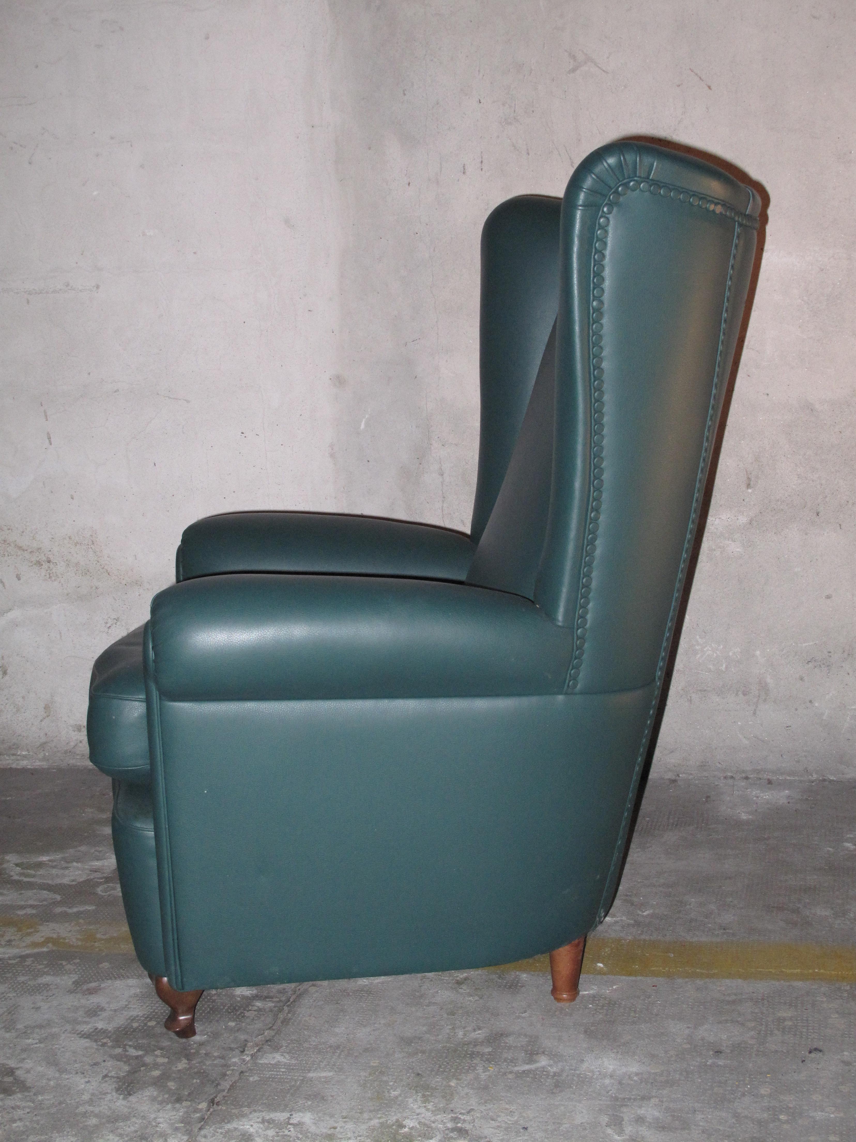 Striking high backed, leather armchair with rolled arms and slight wingtips at the top of the back. Leather wrapped tacks. Sculpted wood legs.