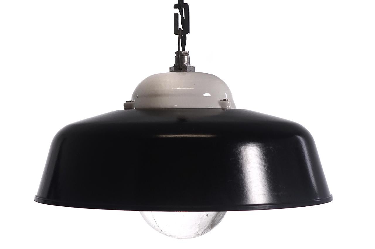 This is a nice seldom seen pair of Industrial lamps. The bulb is covered with a screw-on explosion proof glass shade. The crown is glossy white ceramic. The black shade is some type of composite material. They are very clean and look unused. Priced