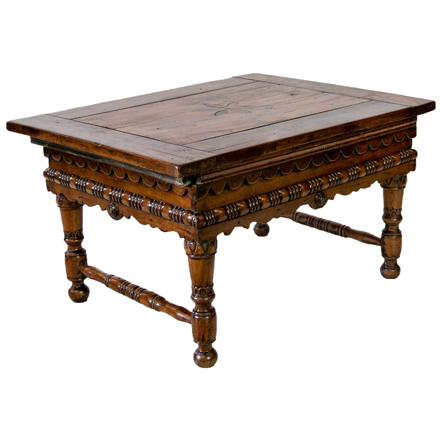 European inlaid fruitwood coffee table, with the center panel having an inlaid stylized flower framed by four thick batten boards. The top is designed to slide in either direction to expose an interior storage compartment. The apron has a repeating