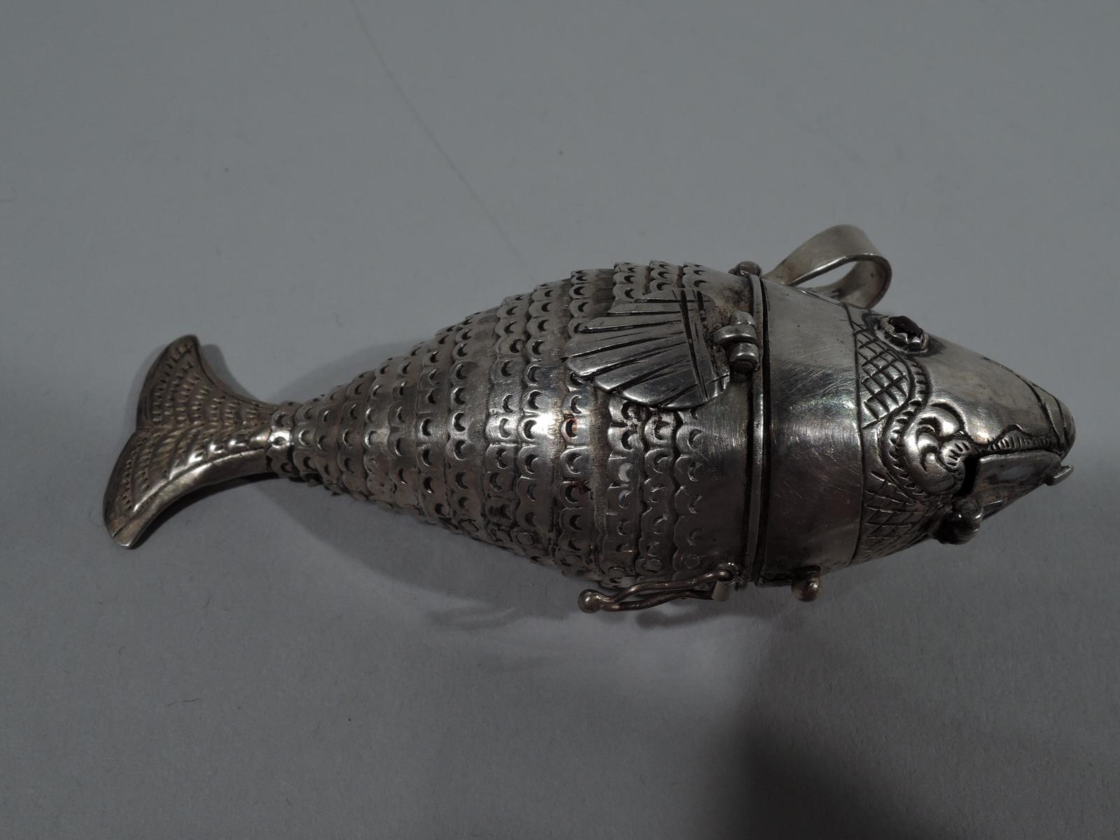 Especiero europeo de plata en forma de pez, S. XIX. Cabeza articulada y boca inferior, y ojos rojos facetados. Cuerpo ancho articulado y festoneado, y aletas y cola articuladas. Anillo suelto. Sin marcar.