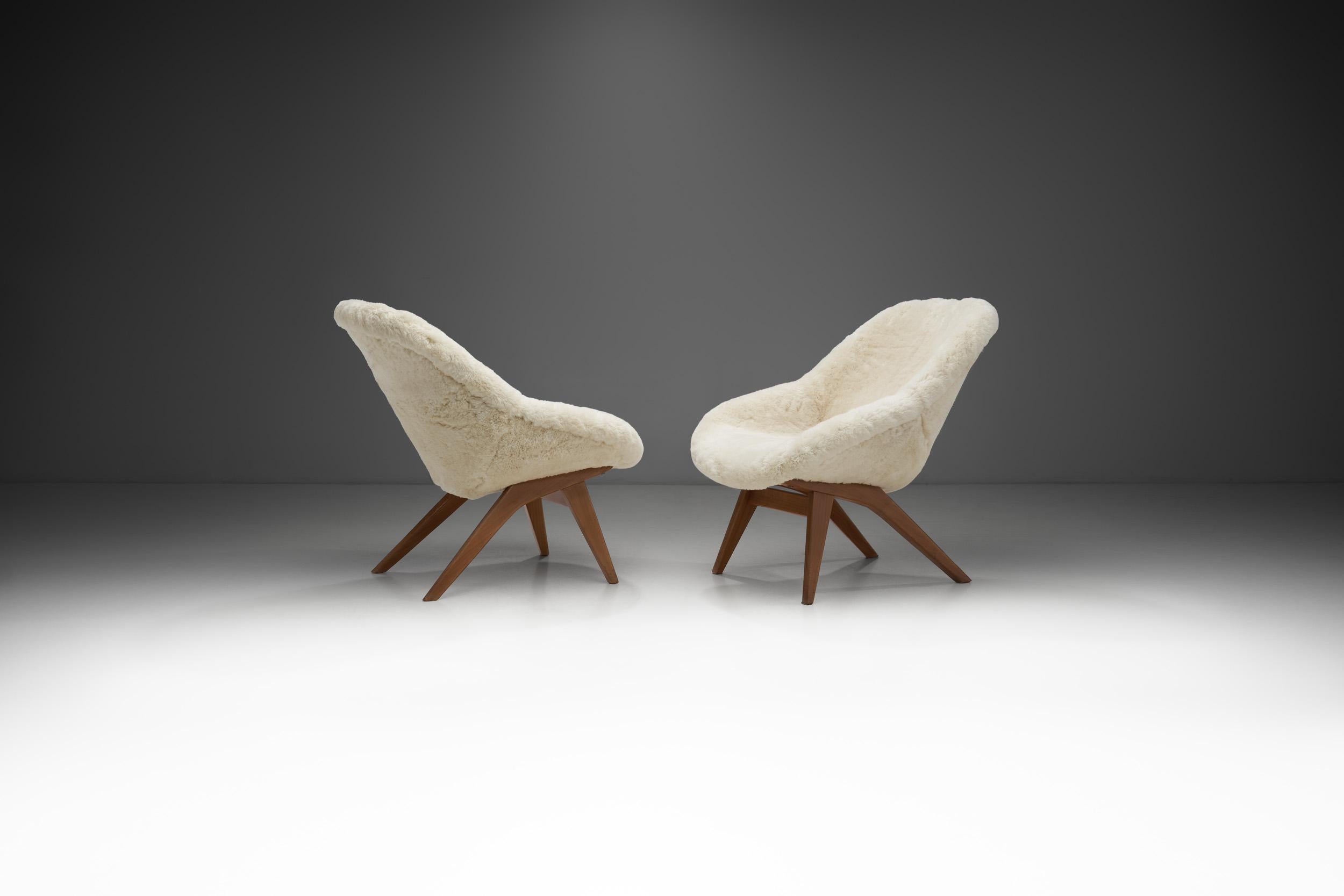These cosy lounge chairs show the homely curviness that defined the design of the 1950s around Europe. This pair of mid-century chairs revolves around high-quality materials, comfort, and the mastery of European cabinetmakers.

This pair has a