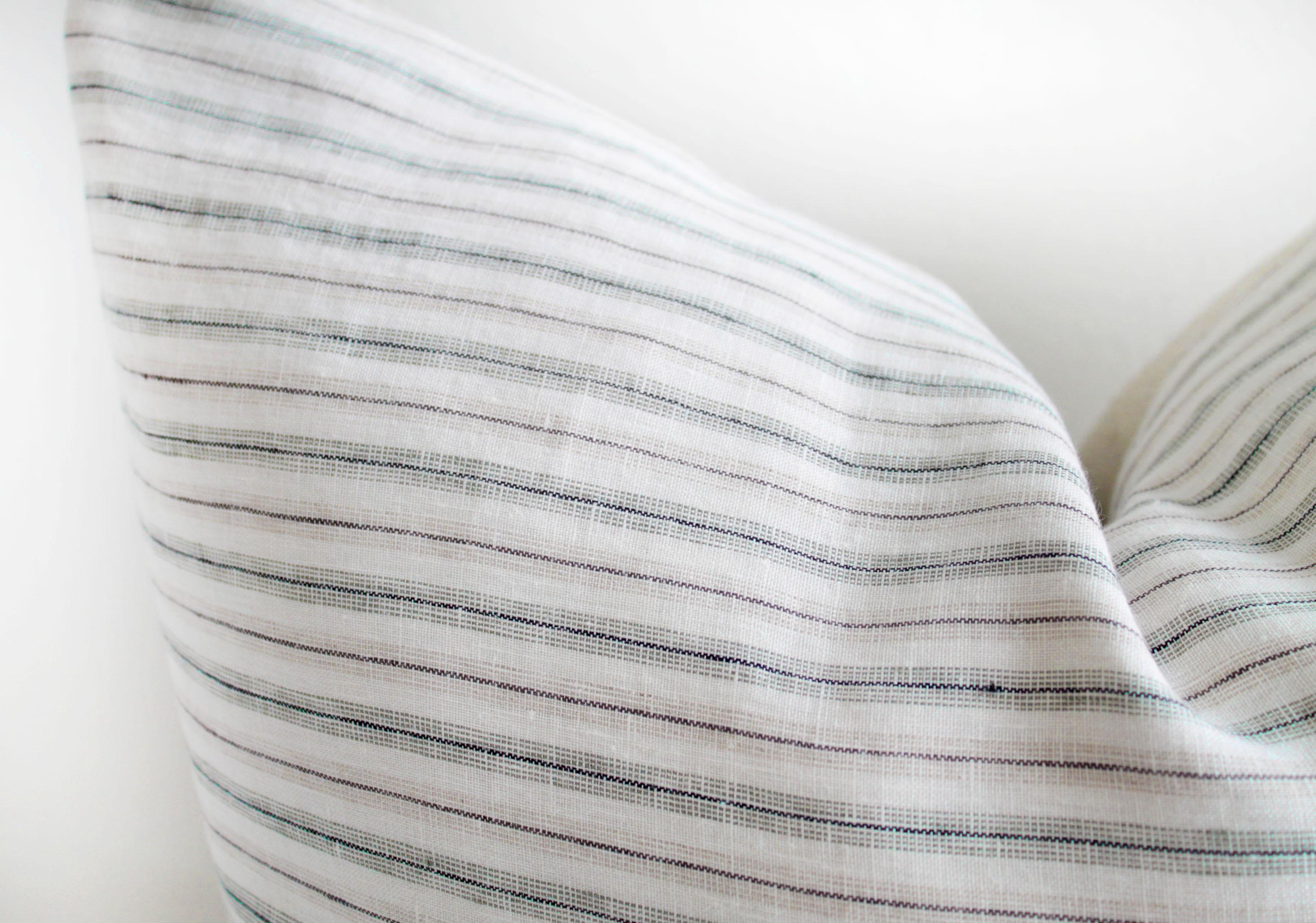 Housse de coussin à rayures européennes en lin bleu, gris et naturel sur fond blanc. Nos oreillers sont fabriqués avec les meilleurs textiles du monde entier. Fabriqué avec soin à partir des meilleurs lins, avec une fermeture à glissière cachée et