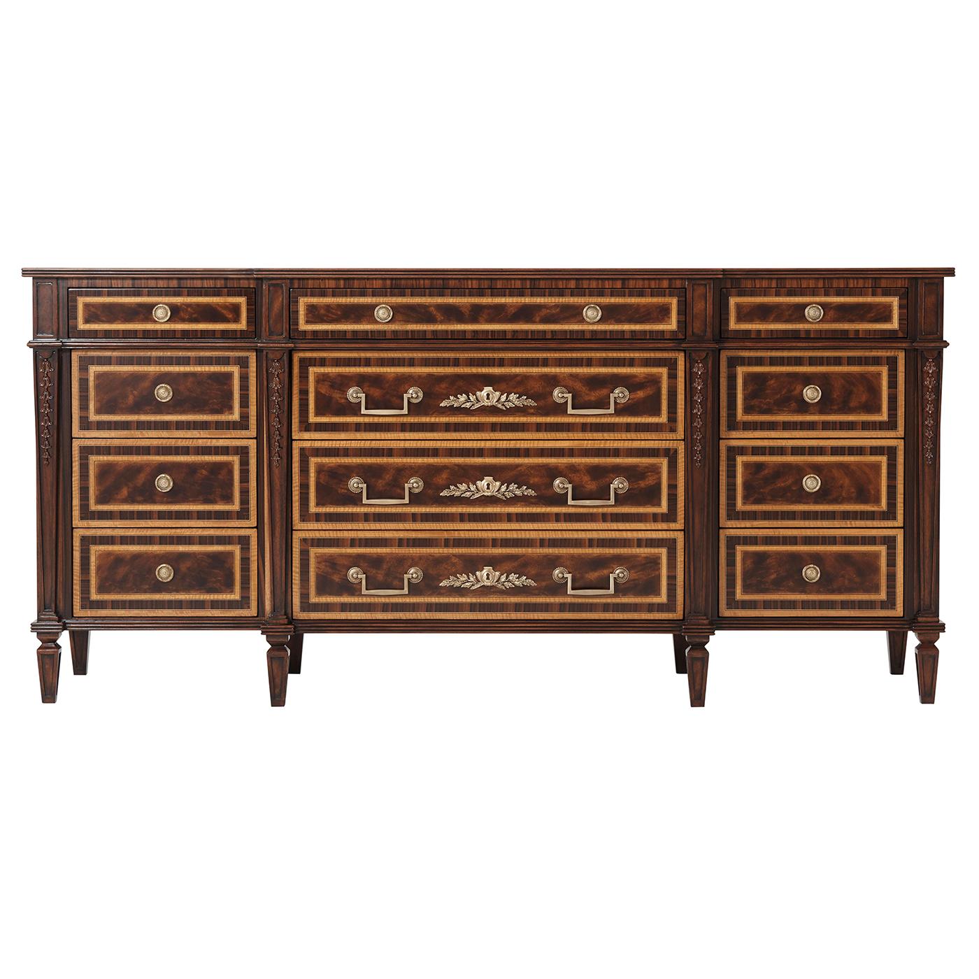 A flame mahogany, movingue and rosewood banded dresser, the breakfront rectangular top with a reeded edge, with three frieze drawers and six short and three long further drawers below, all with fine brass handles and on paneled tapering
