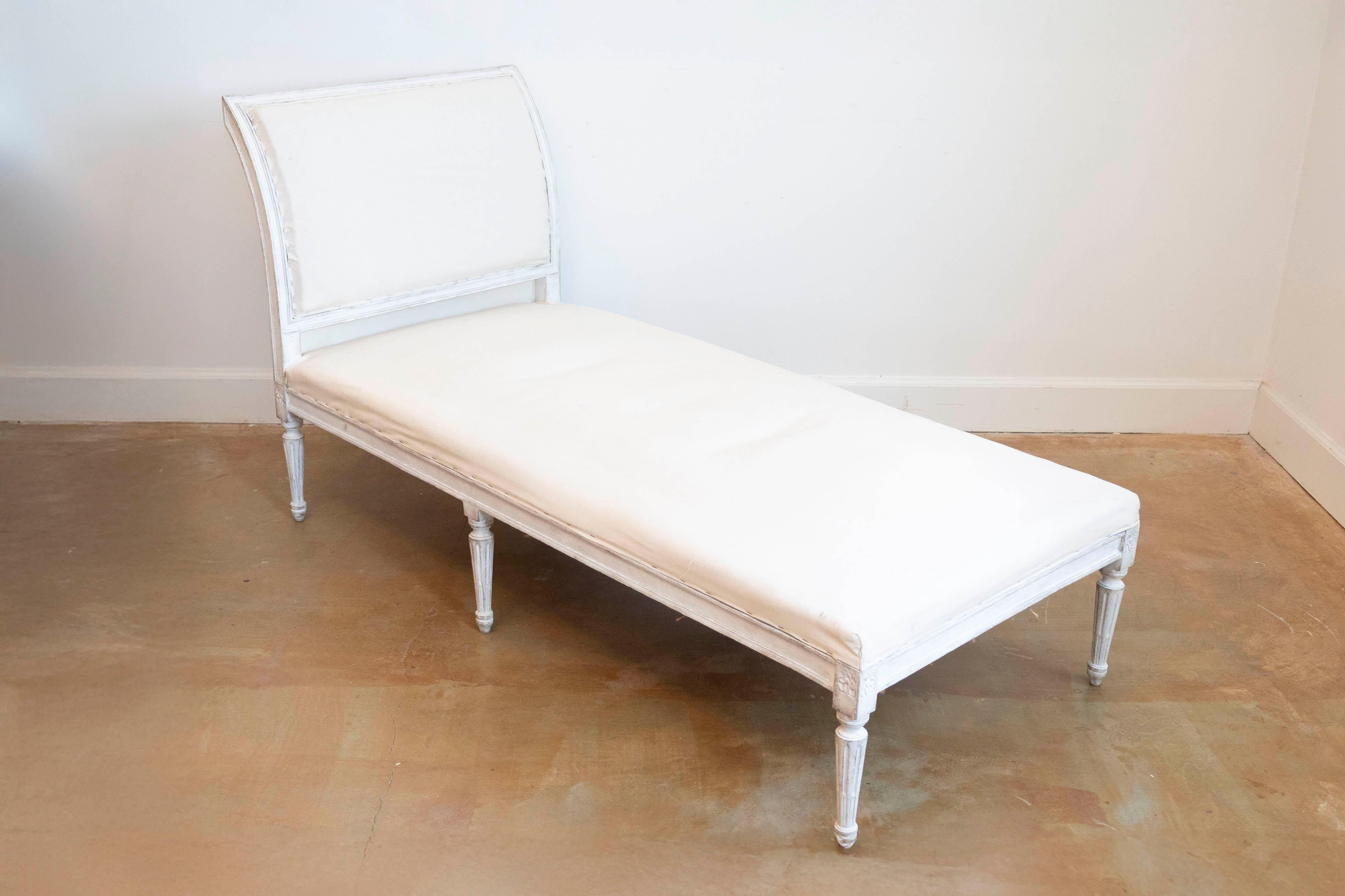 A European Neoclassical period painted wood daybed from the early 19th century, with out-scrolling back, carved rosettes and fluted legs. Created during the second quarter of the 19th century, this Neoclassical daybed features an out-scrolling back