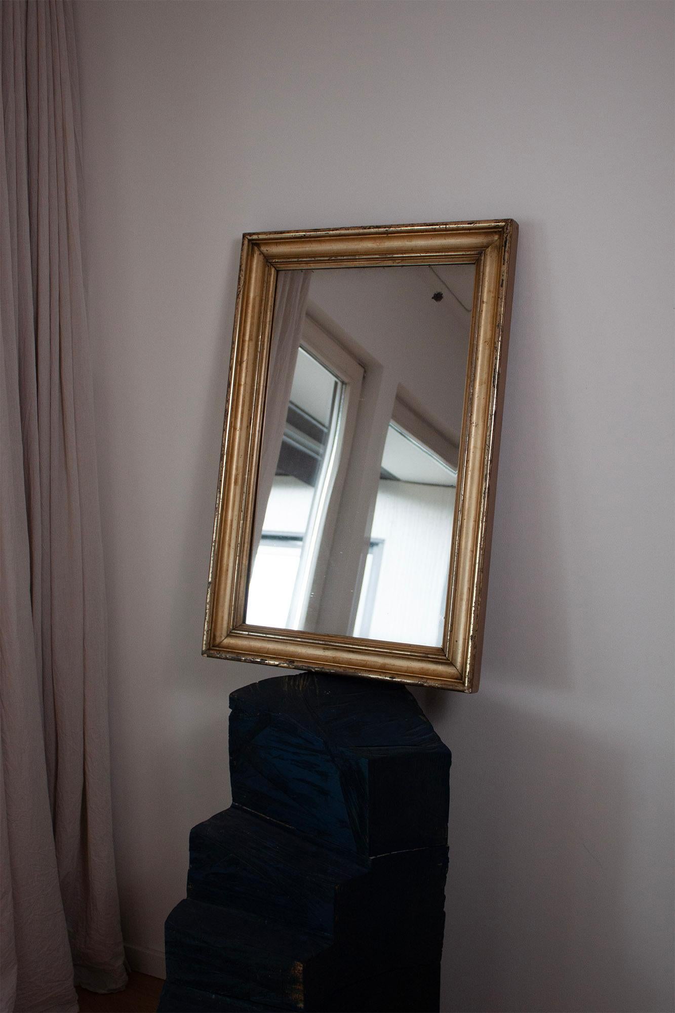 This gilded mirror has still its original mirror plate and wooden frame as well as wooden back panels. This classic design will add an elegant flair to any room. The golden frame, rectangular shape and generous dimensions make it the focal point of