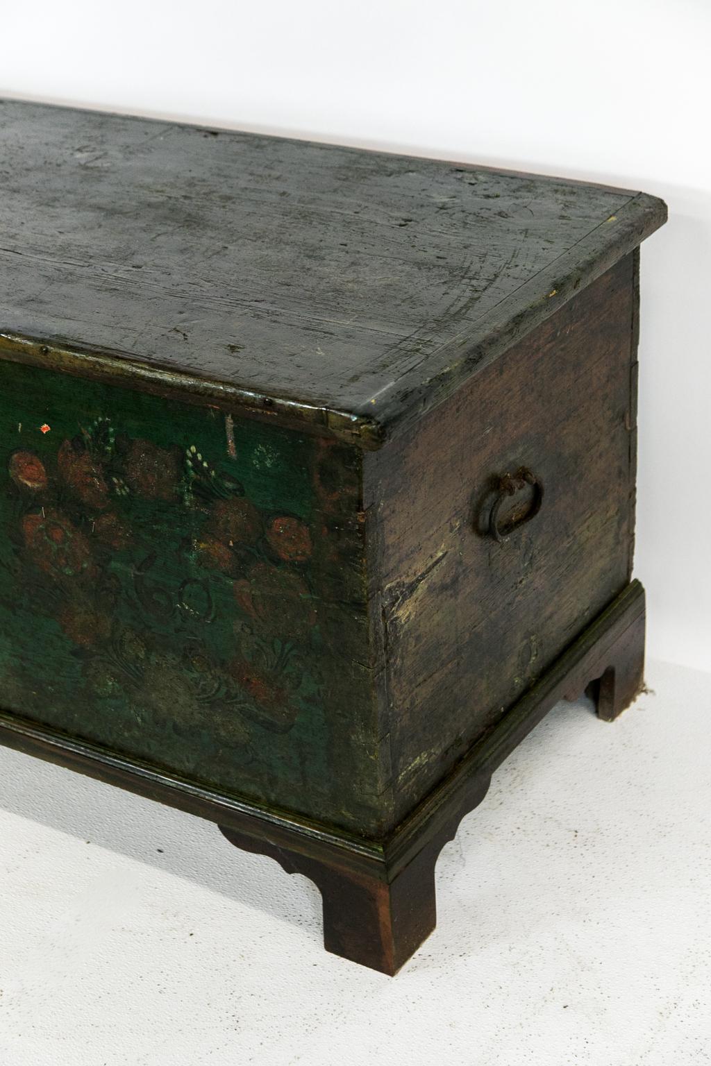 European painted blanket chest, with green being the primary color. It has large exposed dovetails with a center floral bouquet flanked by two floral wreaths.

  