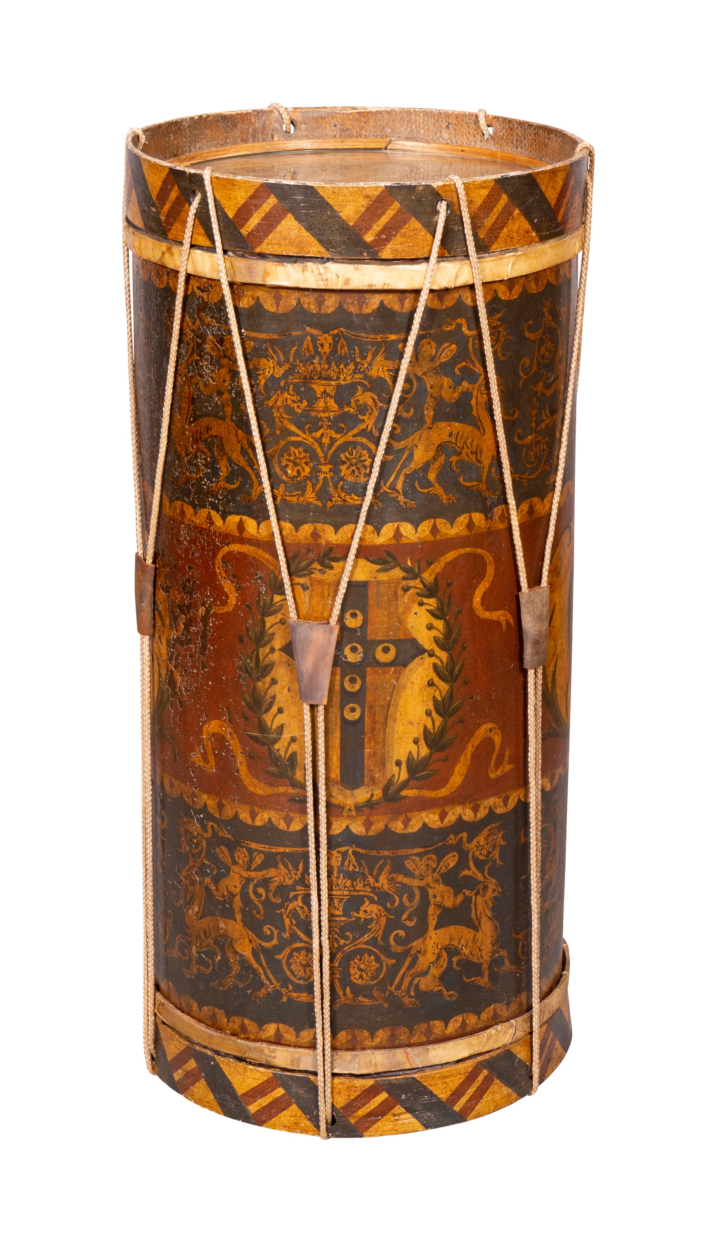 An interesting piece of cylindrical form with vellum tops, the sides decorated with shields and classical design. Strung with rope tied to wood rings at each end.