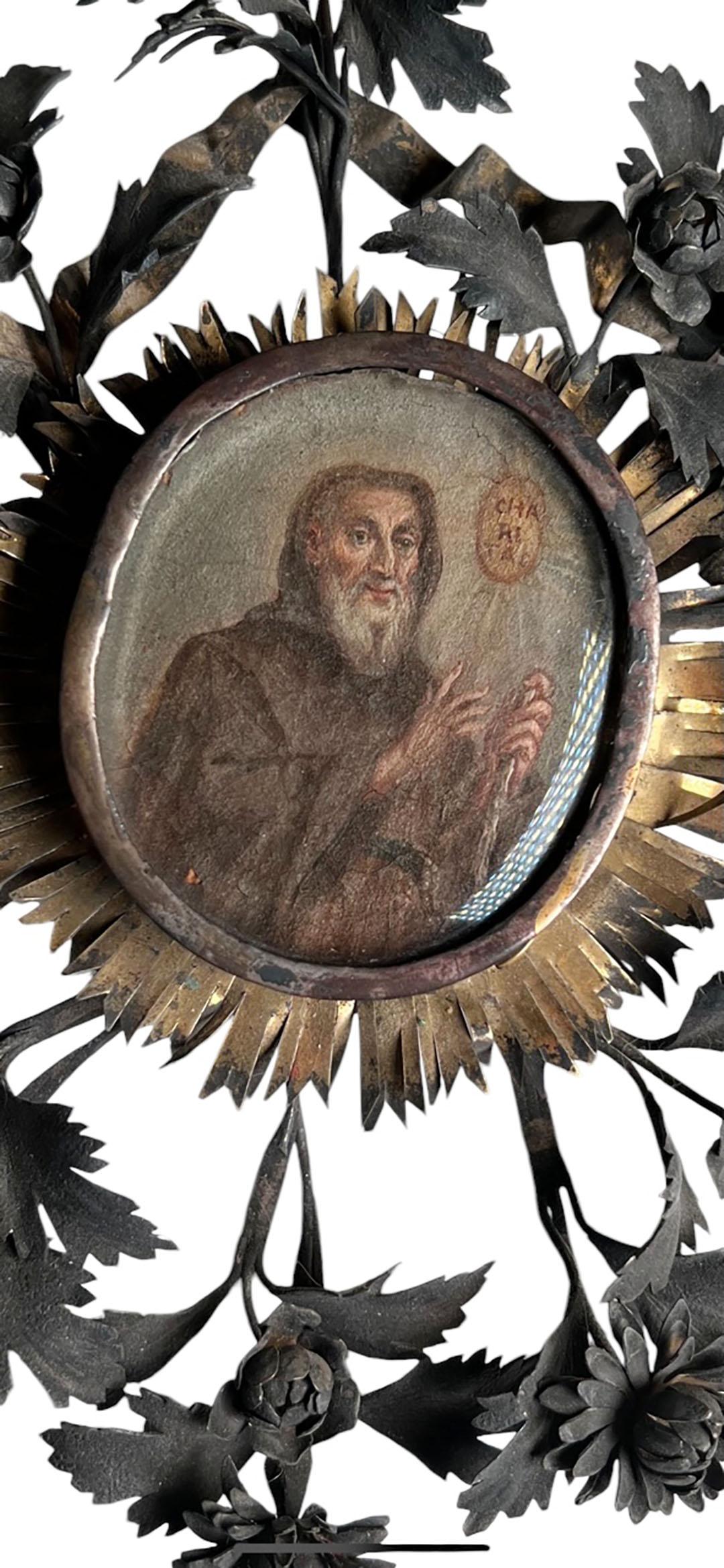 An 18th century saint painted portrait in a frame with silver flowers, leaves and bronze dore sunburst trim. Beveled oval glass. Circa,1750, Italy.