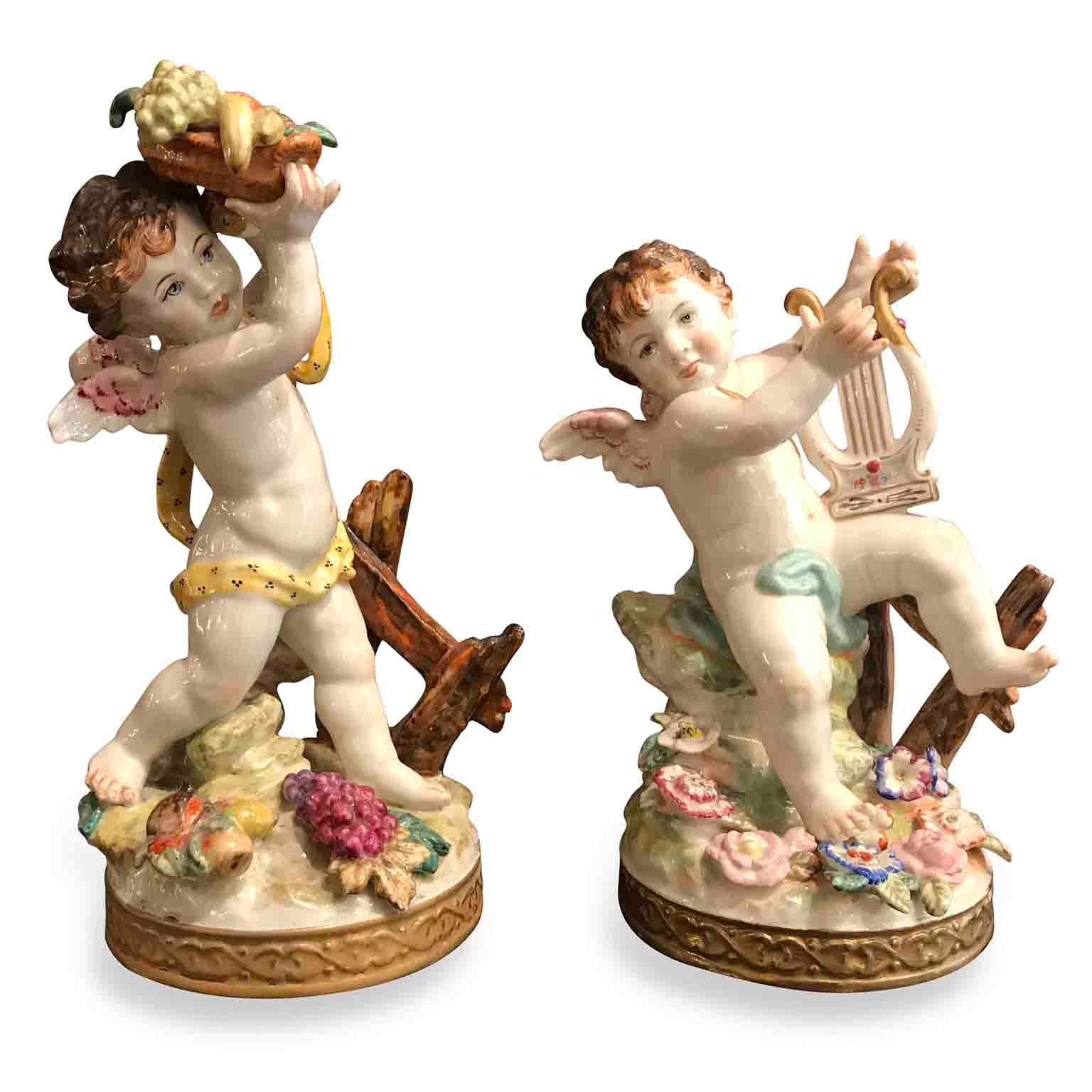 Pair of handmade polychrome porcelain sculptures depicting two winged angels, a pair of fine putti, one holding a fruit basket, Allegory of  abundance, measuring 10,24 inches / 26 cms high and a Lyre player Cherub, allegory of music,  8,66 inches /