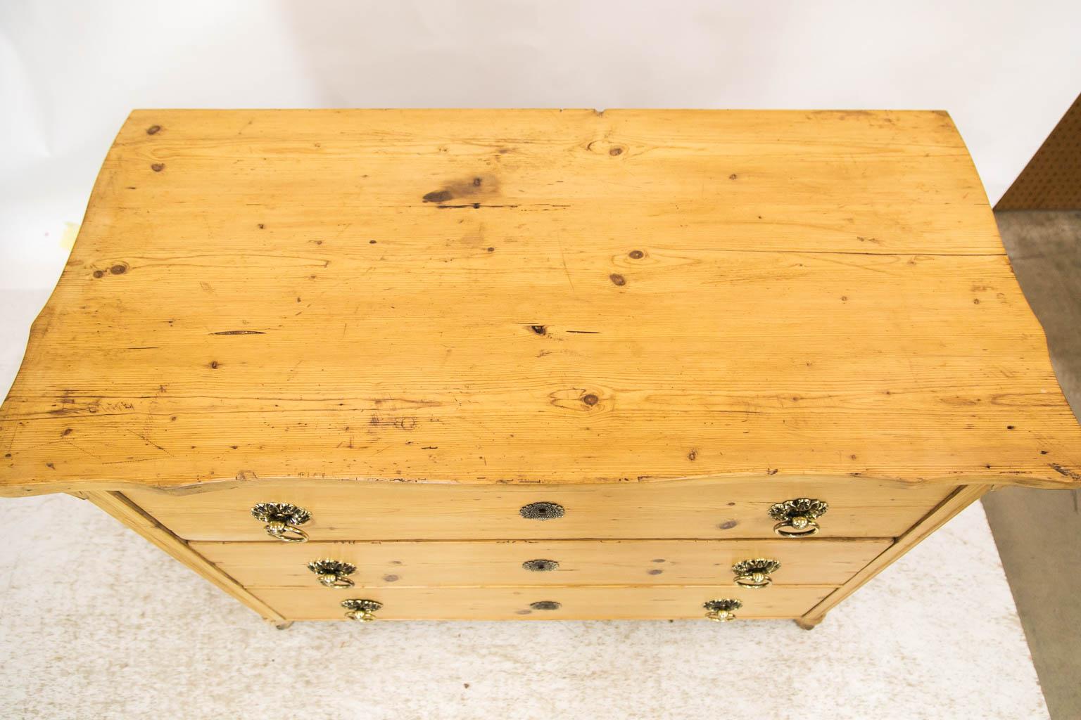 This chest has a shaped top with fluted chamfered stiles with a stylized acanthus bracket at the top terminating in corresponding carved feet. There is a coved molding supporting the top on all three sides. The locks are original. Hardware is later.