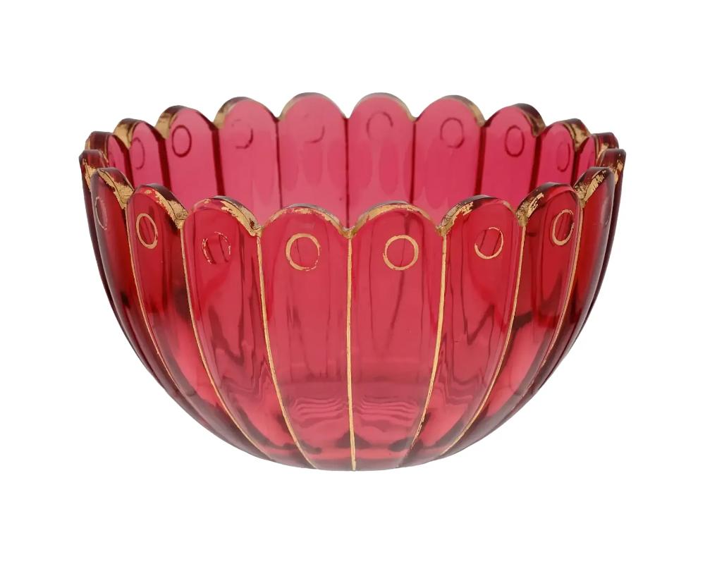 A vintage European, probably Czech, Bohemian glass bowl in a Ruby red shade. The bowl is made in a panel design, adorned with scalloped and gilded edges. Unmarked. Circa: the first half of the 20th century. Antique and Vintage European Glass Bowls,