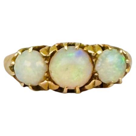 Descubre la belleza atemporal de este anillo vintage de los años 50, elaborado en oro amarillo de 14 quilates y con tres exquisitos ópalos blancos que suman aproximadamente 1,6 quilates. Cada ópalo presenta un cautivador juego de colores, con el