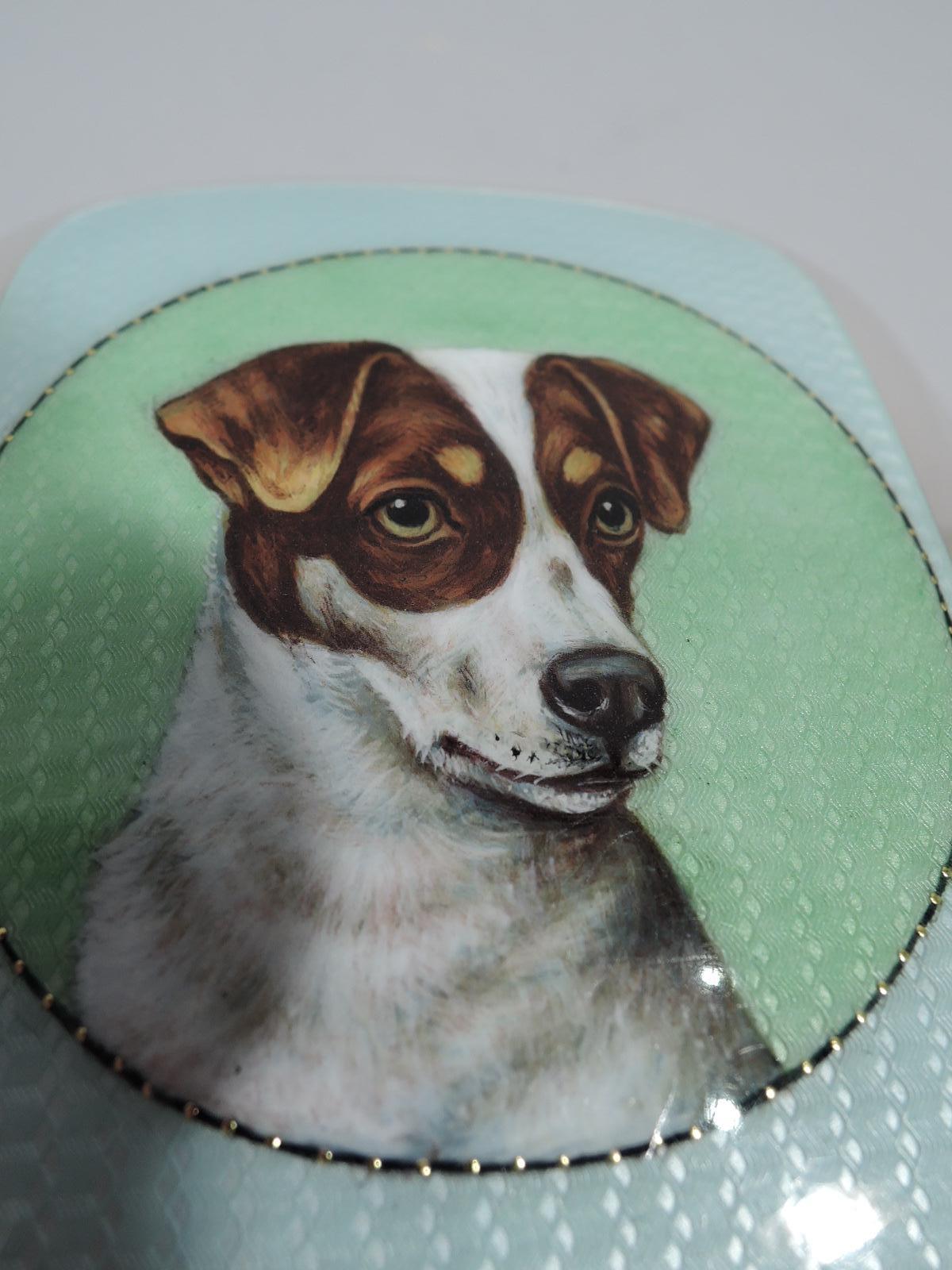 European silver and enameled dog case, ca 1910. Rectangular, curved, and hinged. On cover is the bust of a Jack Russell terrier set in green guilloche rondel. A super-cute pup portrait with floppy ears and concentrated gaze. Back plain with engraved