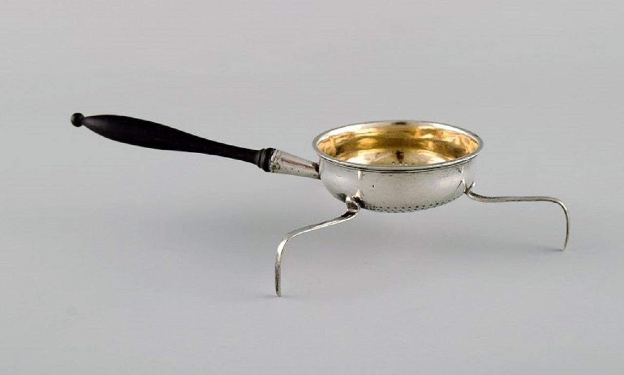 European silversmith. 
Antique silver tea strainer on tripod with shaft in turned ebony. Gilded inside. 
1800s.
Measures: 12.5 x 5.5 cm.
In excellent condition.
Stamped.
Large private collection of European silver tea strainers.