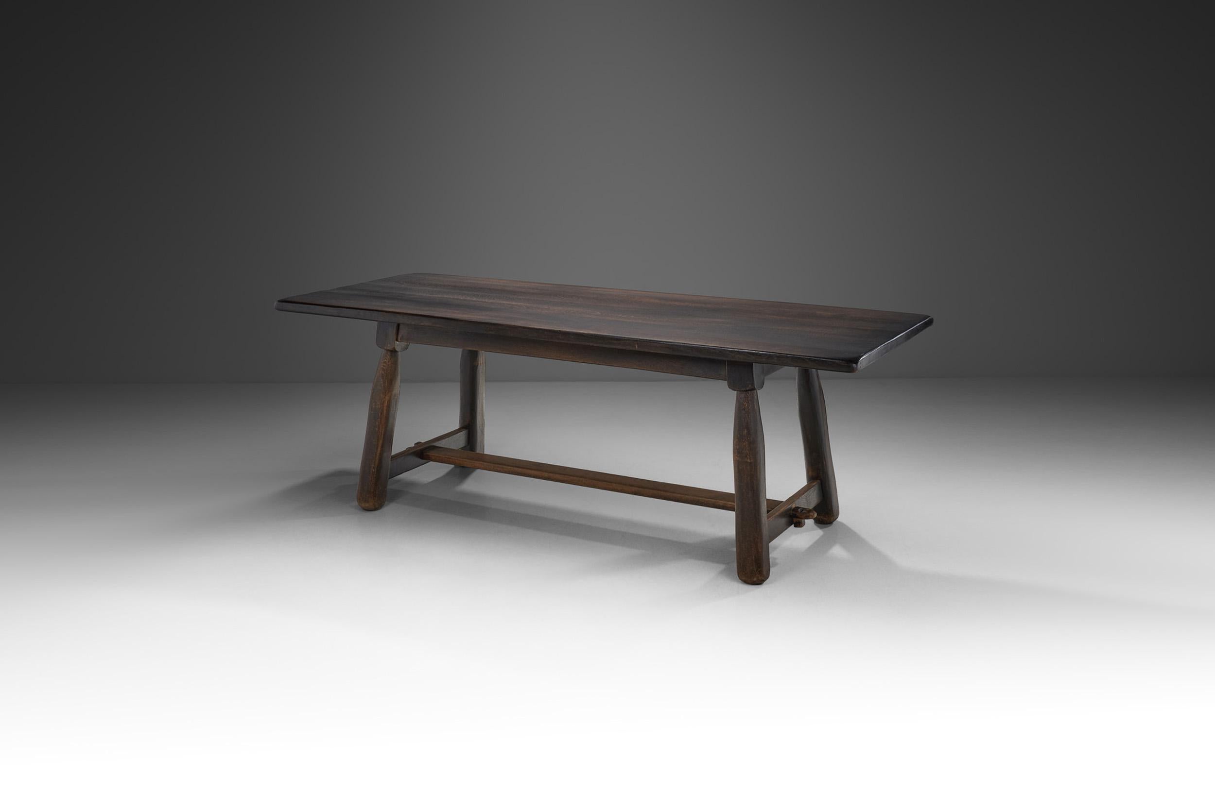 Questo caratteristico tavolo da pranzo in legno massello strizza l'occhio al design modernista con la tradizionale maestria europea di metà secolo. Il design trasmette una visione della società e della cultura in cui è stato prodotto: la vicinanza