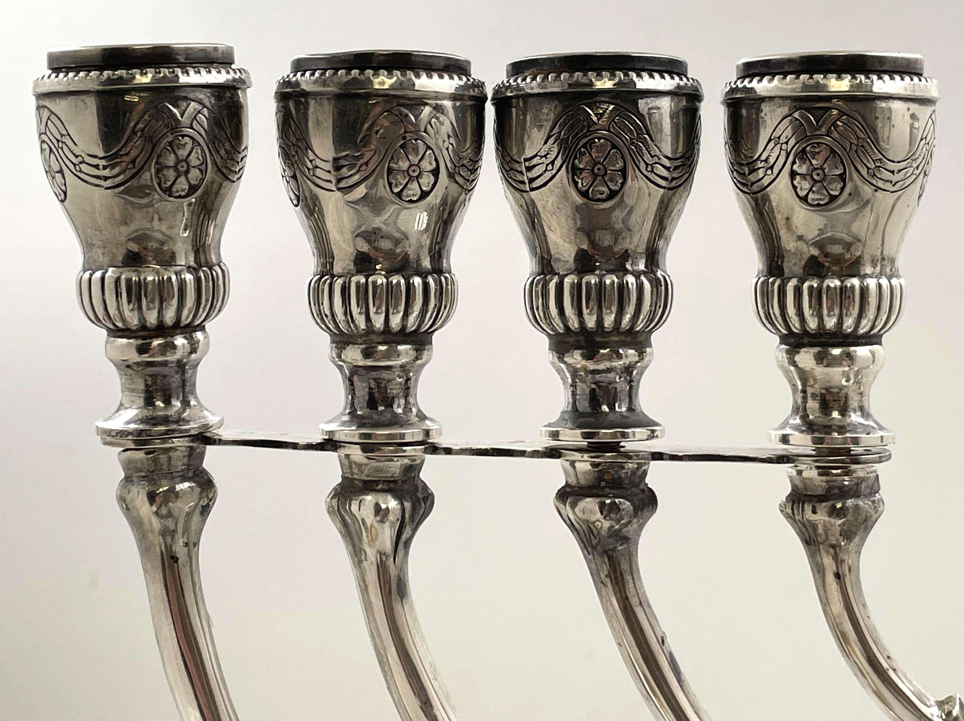 European, sterling silver menorah, from the early to mid-20th century, adorned with engraving floral and geometric motifs, including a detachable arm and oil pourer. It measures 15 1/2'' in height by 12 3/4'' in width by 5'' in depth, weighs 31.6