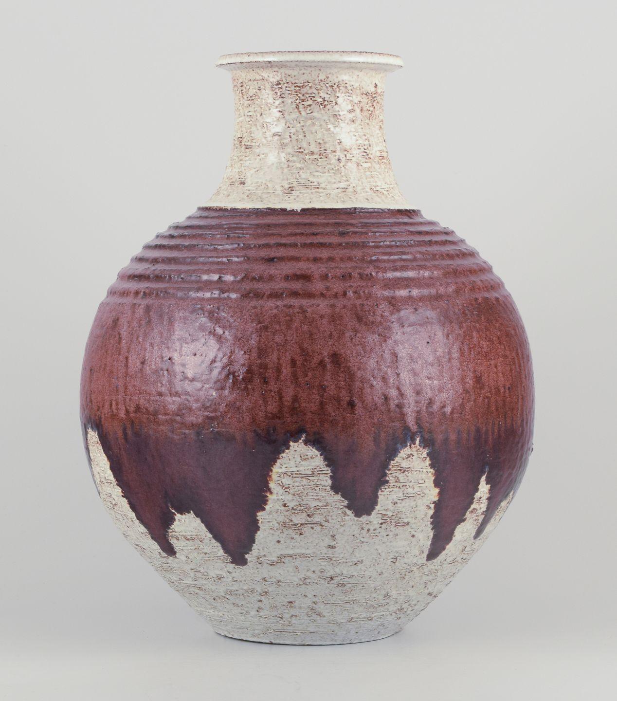 Pre-owned goods are exempt from import duties for U.S. customers. 
Therefore, no import tariffs will be applicable to your purchase.

European studio ceramicist.
Unique floor vase in ceramic.
Flowing glaze in brown hues on a sand-colored