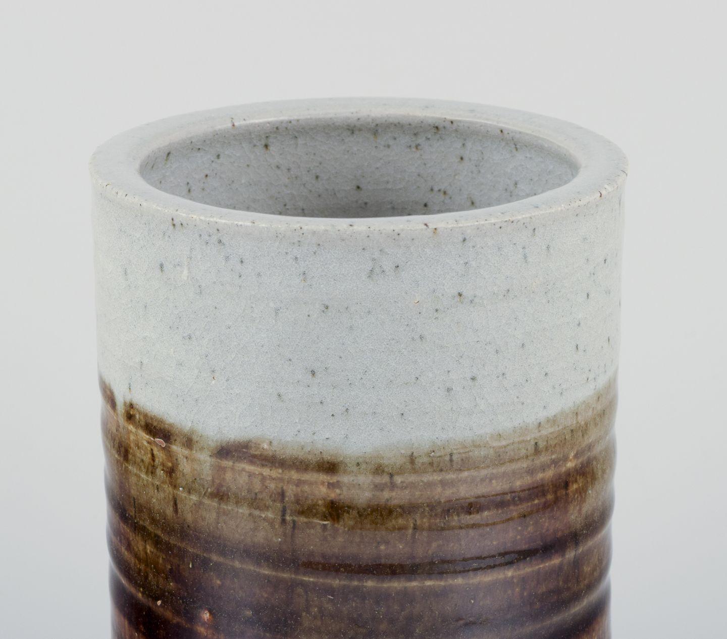 Céramiste d'atelier européen.
Vase unique en céramique, de forme cylindrique.
Glacis dans les tons gris et bruns.
La partie inférieure n'est pas émaillée.
Rencontres : Ca. 1980s.
Signature de l'artiste indistincte.
En excellent état, avec de petites