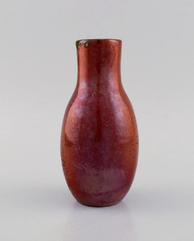 Europäischer Studiokeramiker. Einzigartige Vase aus glasiertem Steingut. Schöne metallische Glasur in Rottönen. 
Mitte des 20. Jahrhunderts.
Maße: 17 x 8 cm.
In ausgezeichnetem Zustand. Zwei Glasurblasen.