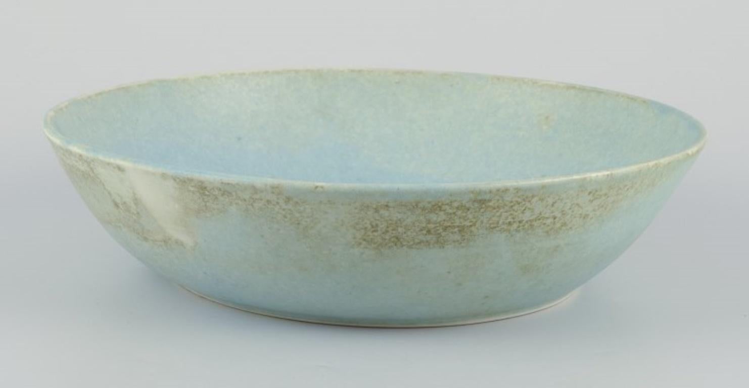 European studio ceramicist.
Very large bowl. 
Glaze in light blue and sand-coloured tones.
Dating: Ca. 1980s.
Indistinct artist signature.
In perfect condition.
Dimensions: D 29.5 cm. x H 7.0 cm.