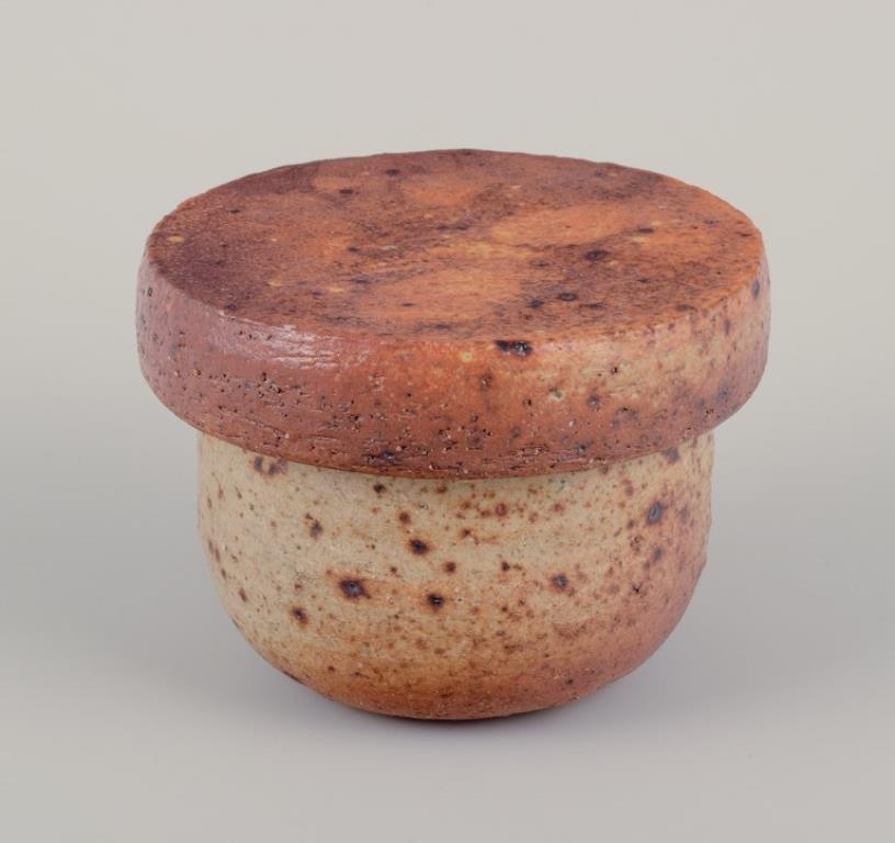 European studio potter. 
Two unique ceramic jars, one with a lid. Glazed in earth tones and blue-gray hues. 
In excellent condition, with minimal chips in the opening of one jar (see photo). 
One of the jars is signed with a monogram. 
Approximately