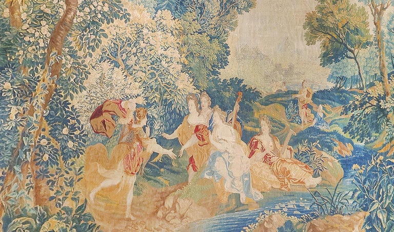 This engaging antique European tapestry is an extremely finely woven wool and silk from 1650s Belgium, Brussels as a unique story of Verdure Love Scene .The entire scene is set within an abundant woodland setting of trees, bushes and various flora