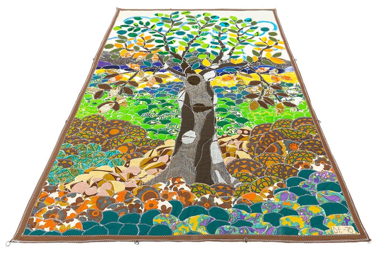 Esta obra de arte textil vintage de Doris Fonk es una composición vibrante y dinámica que capta la belleza de la naturaleza a través de intrincados motivos y ricos colores. El elemento central es un majestuoso árbol con ramas que se extienden hacia