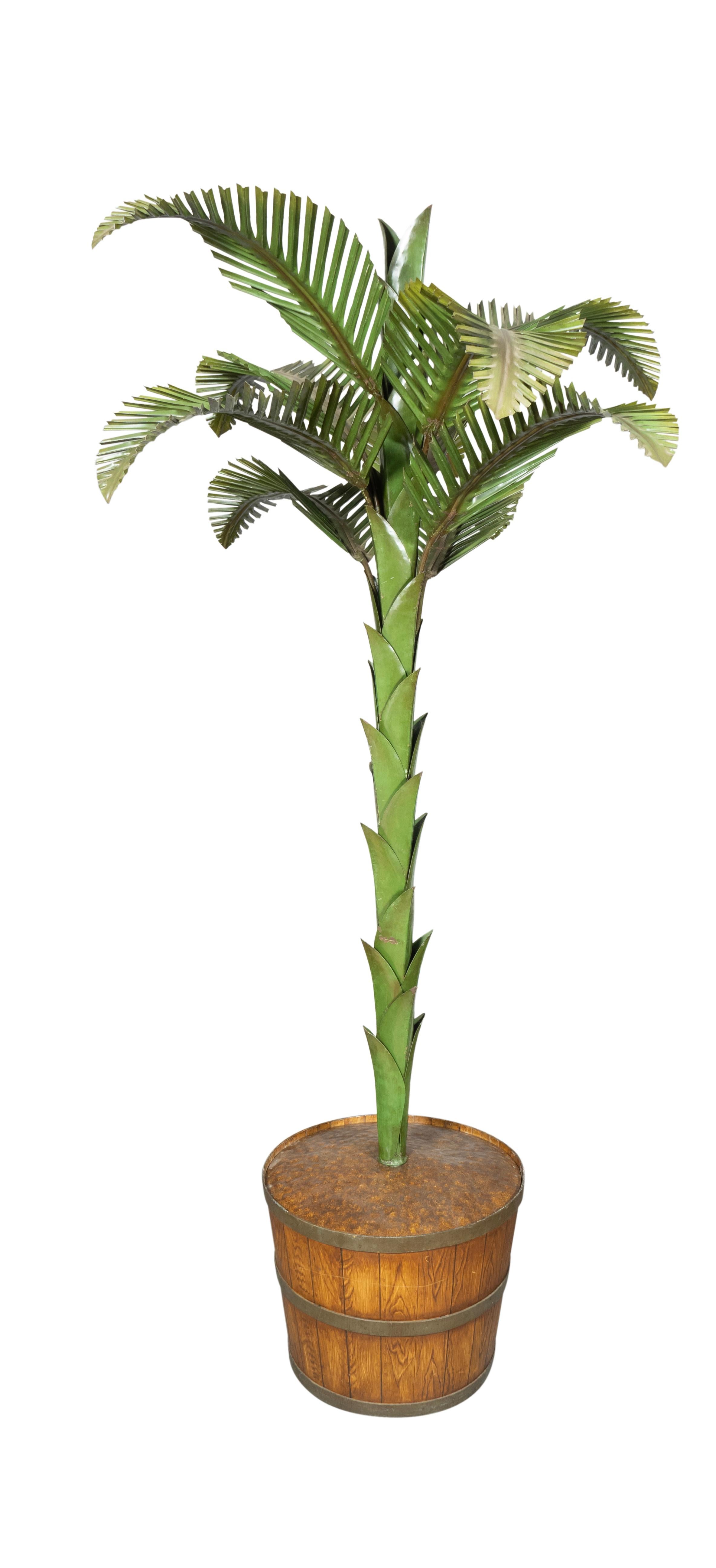 With a painted tole planter painted to imitate a wood stave pot. The palm with copper stem and green palm fronds. Lacking the top clustered frond. Nine branches.