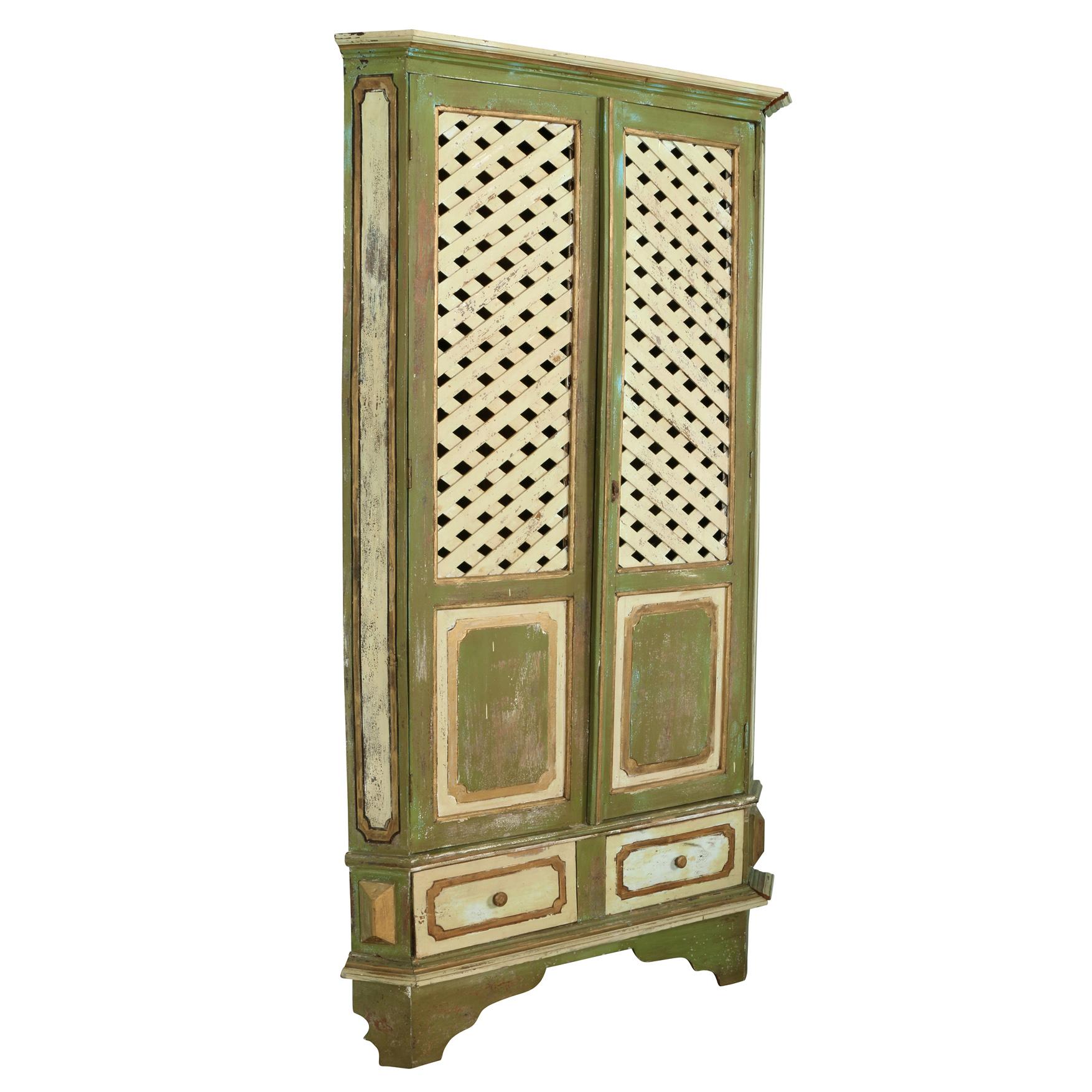 European trelliage green and antique white painted corner wood cabinet. Two doors open to reveal storage shelves. Two drawers at bottom.