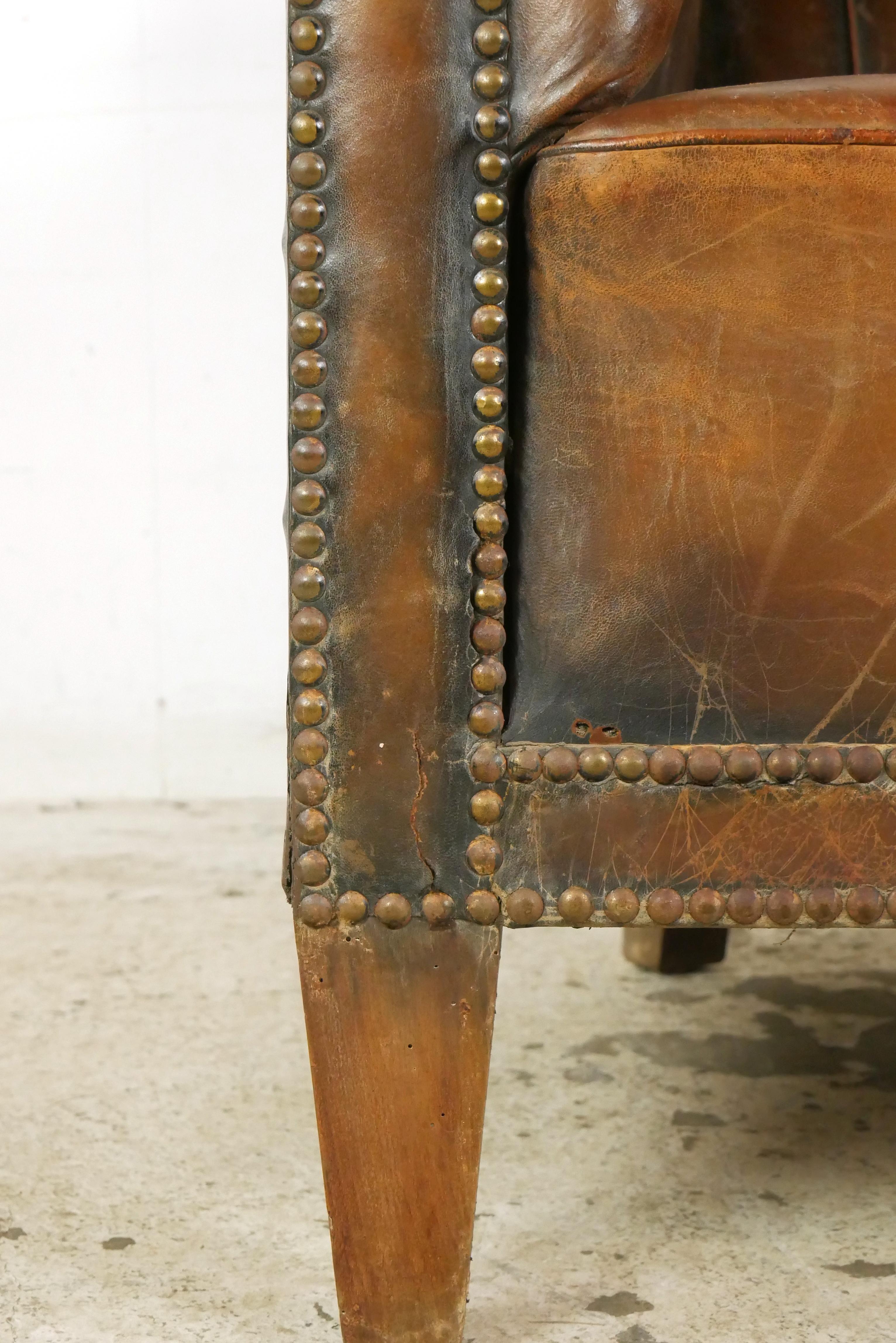 French made brown leather club chair with a tufted back and studded details. Please refer to the pictures for a full view of the condition. Good condition with surface wear from prior use. One available. Please note, this item is located in our