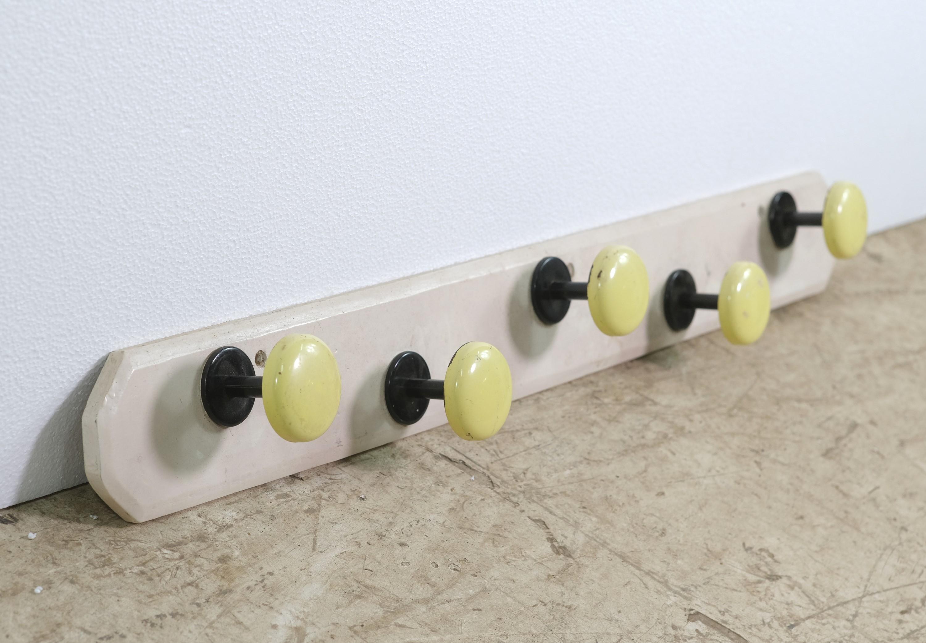 Wall mounted coat rack featuring 5 steel round hooks in a yellow finish. The backing plate is wood done in a white color. From Europe. Please note, this item is located in our Scranton, PA location.