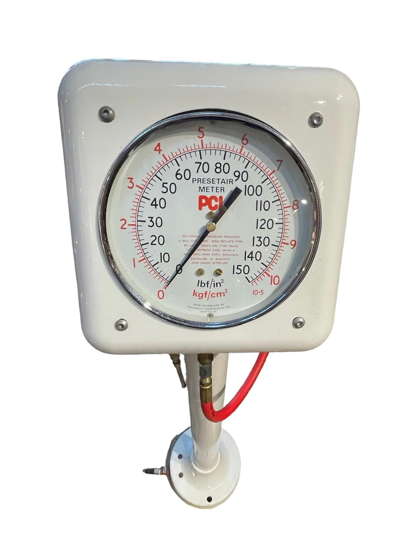 This is a PCL Preset Air meter pedestal mounted. It is painted white and has a red  air hose. It meters the air. The hose can be hanged in a hook in the back. It provides automatically inflated balanced tire pressures against a precision- master
