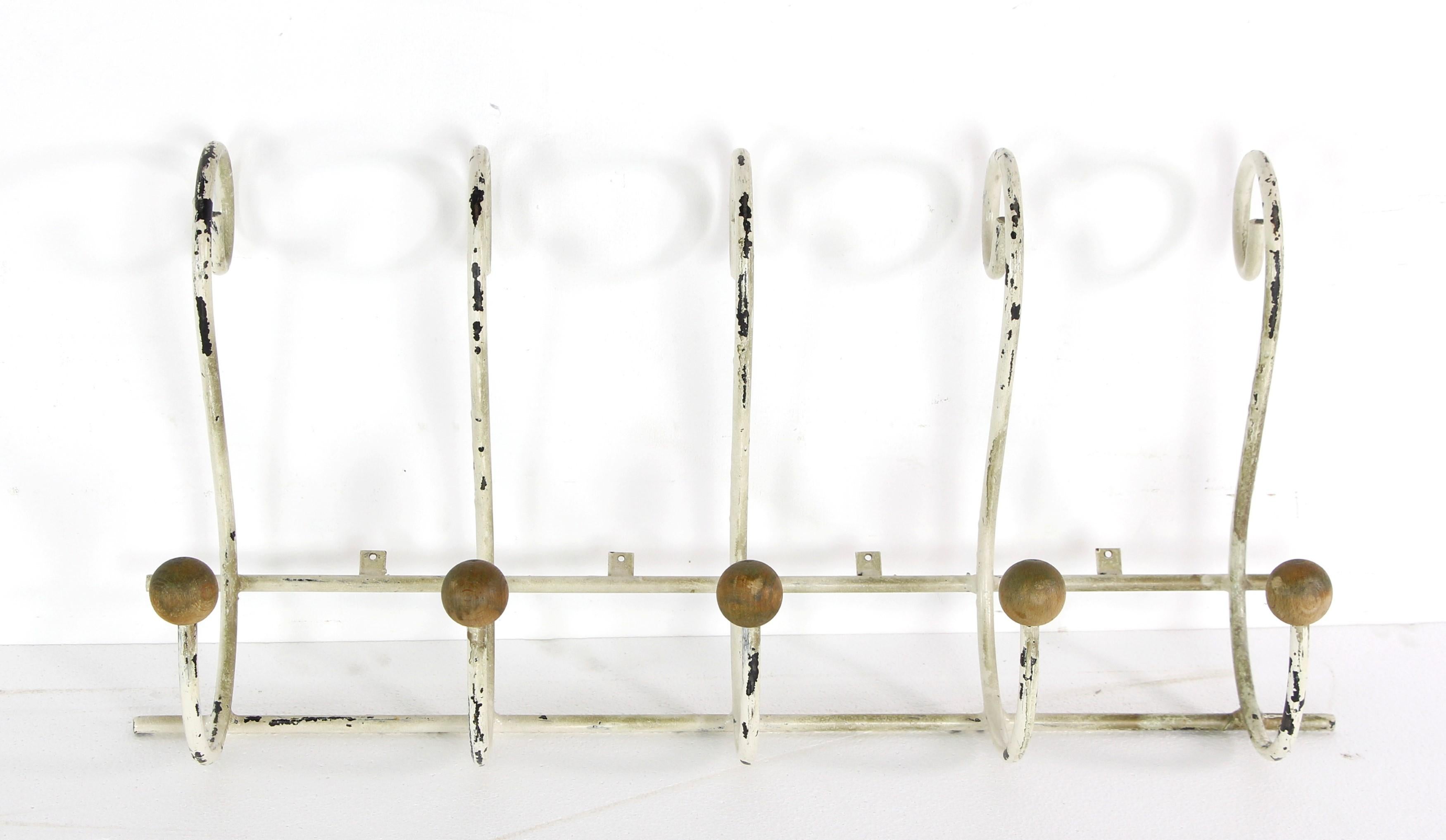 This European style white painted distressed steel wall rack features five double arm hooks, with wooden balls attached to the bottom hooks. This piece offers a rustic and charming storage solution, blending functionality with decorative accents for
