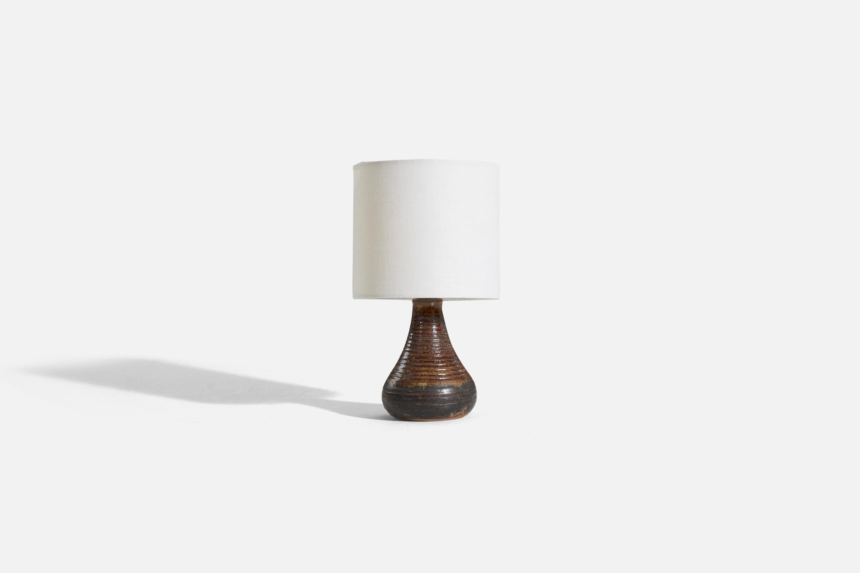 A brown and black, glazed stoneware table lamp, designed by Eva Bengtsson and produced for Åsbo Keramik, Sweden, c. 1970s.

Sold without lampshade. 
Dimensions of Lamp (inches) : 7.25 x 3.875 x 3.875 (H x W x D)
Dimensions of Shade (inches) : 6