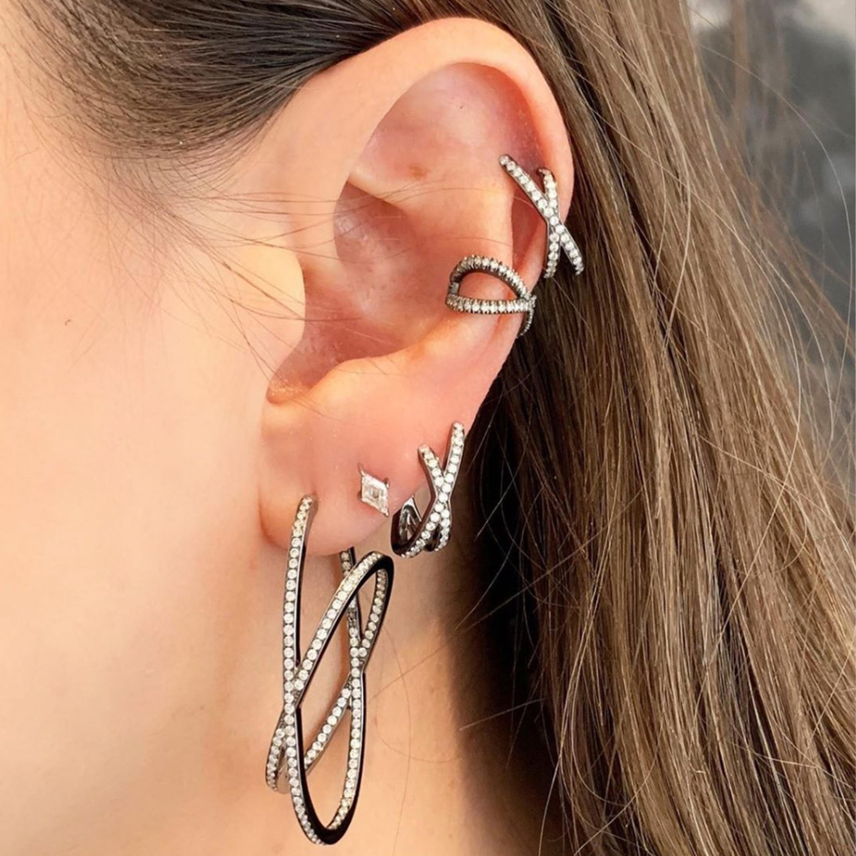 18K Blackened White Gold White Diamonds - Small Orbit Hoops

The Orbit Hoops continue to evolve the iconic X shape on the ear, wrapping around to create the illusion that they go through two piercings.  The hoops are hinged in the center of the back